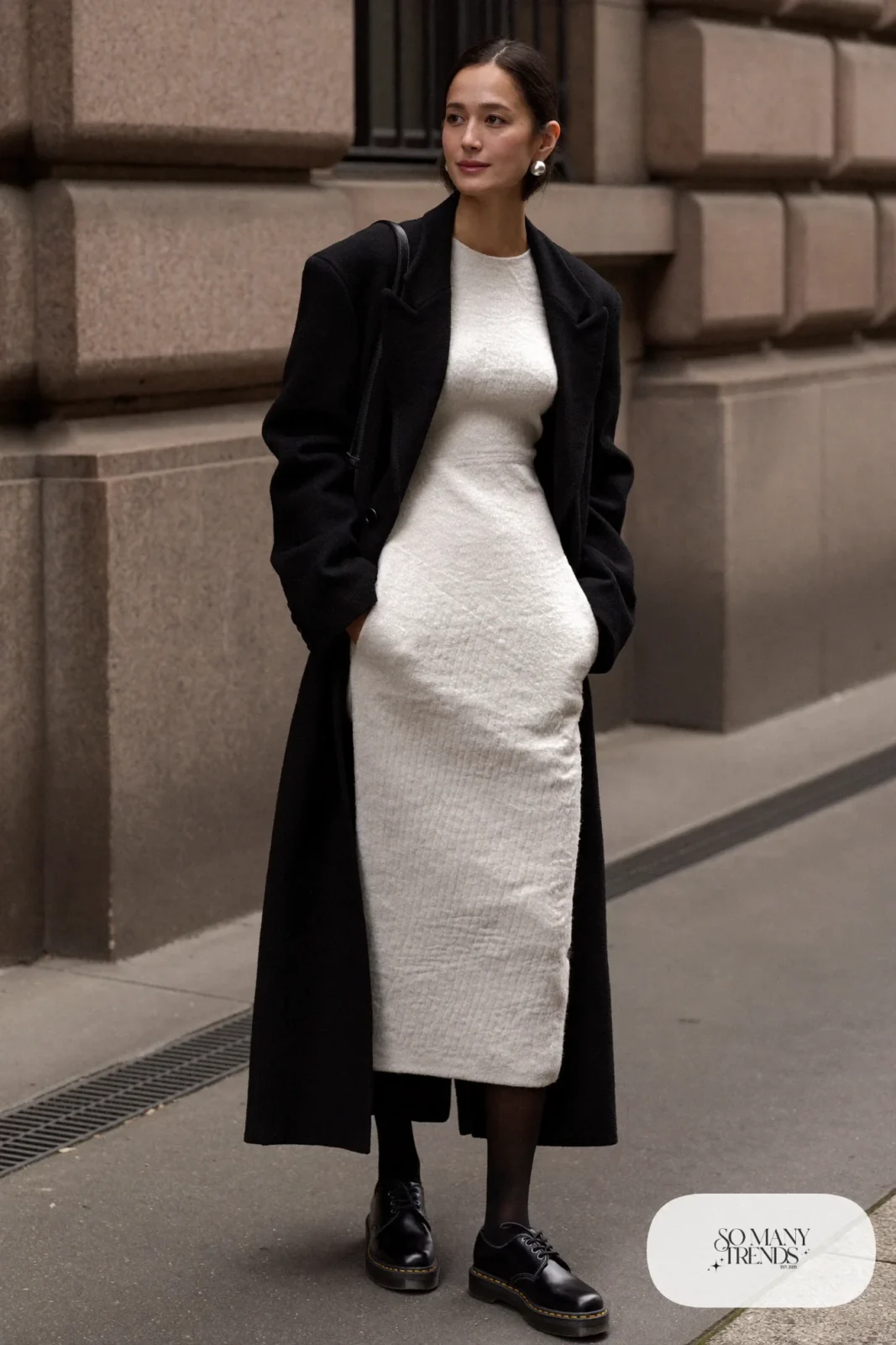 Woman in pearl white knit midi dress, black tights, black Doc Martens loafers and a black wool coat, outfit 9