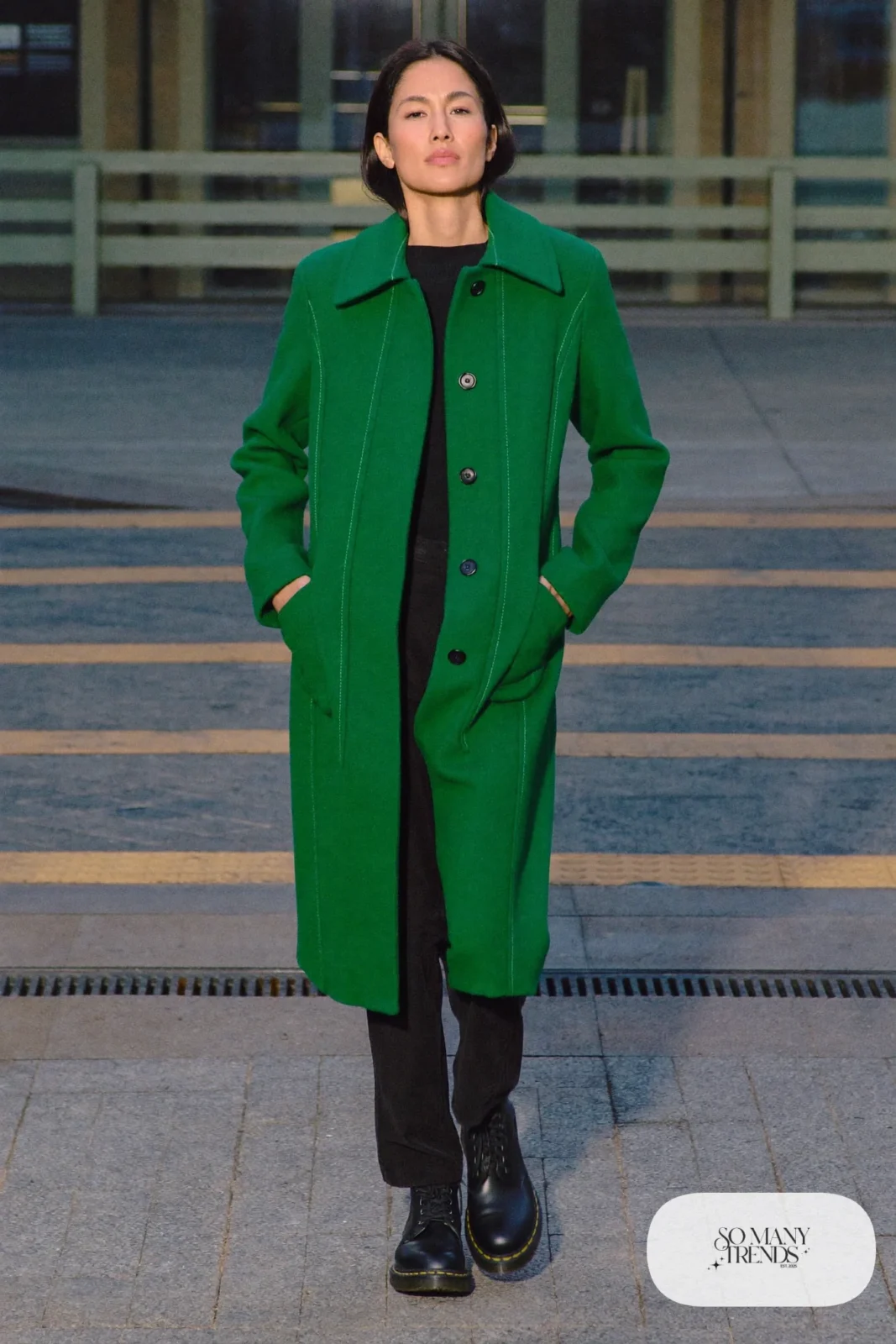 Woman in emerald wool coat, black knit top, black pants and black Doc Martens boots, outfit 19