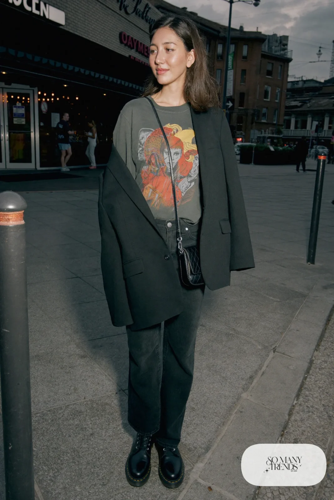 Woman in faded black band tee, oversized black blazer, black jeans and black Doc Martens 1460 boots, outfit 20