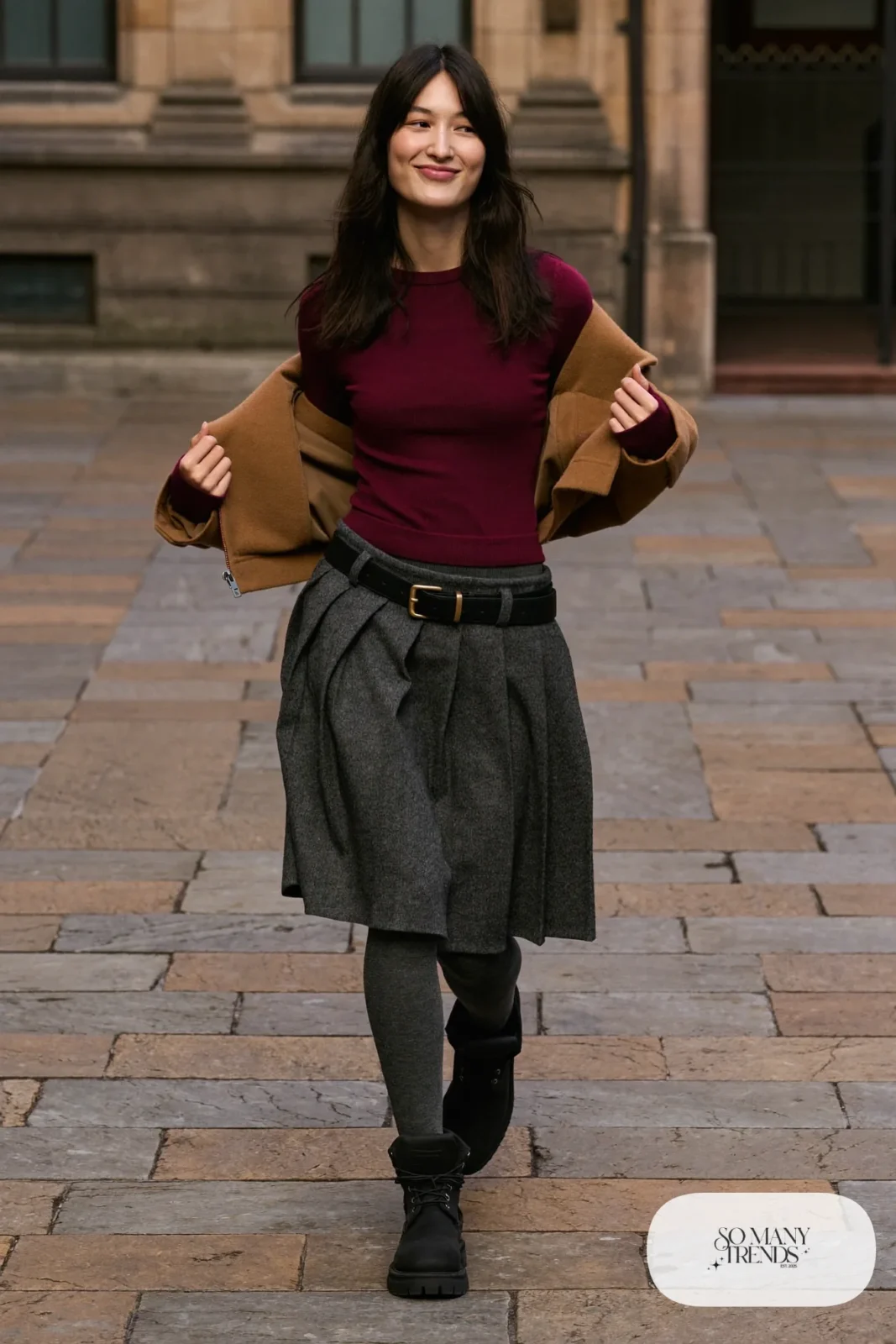 Woman in charcoal pleated midi skirt, burgundy sweater, charcoal tights and black Timberland-style boots, outfit 7