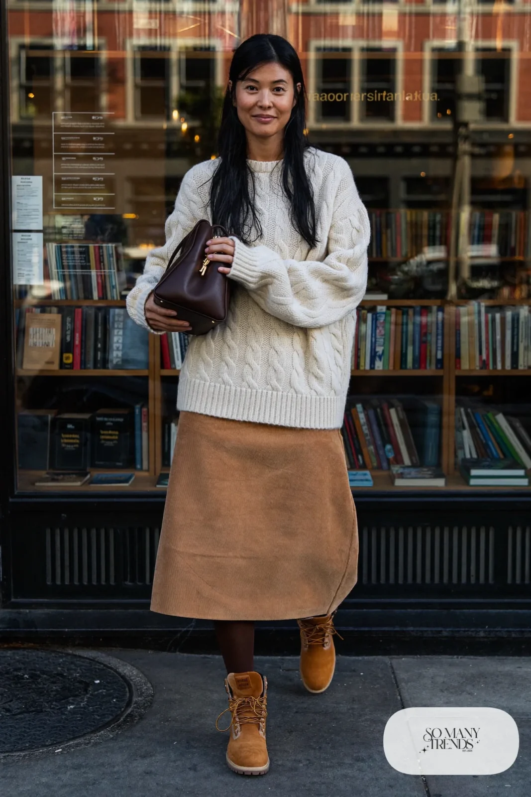 Woman in camel corduroy midi skirt, cream fisherman sweater, brown tights and wheat Timberland-style boots, outfit 10