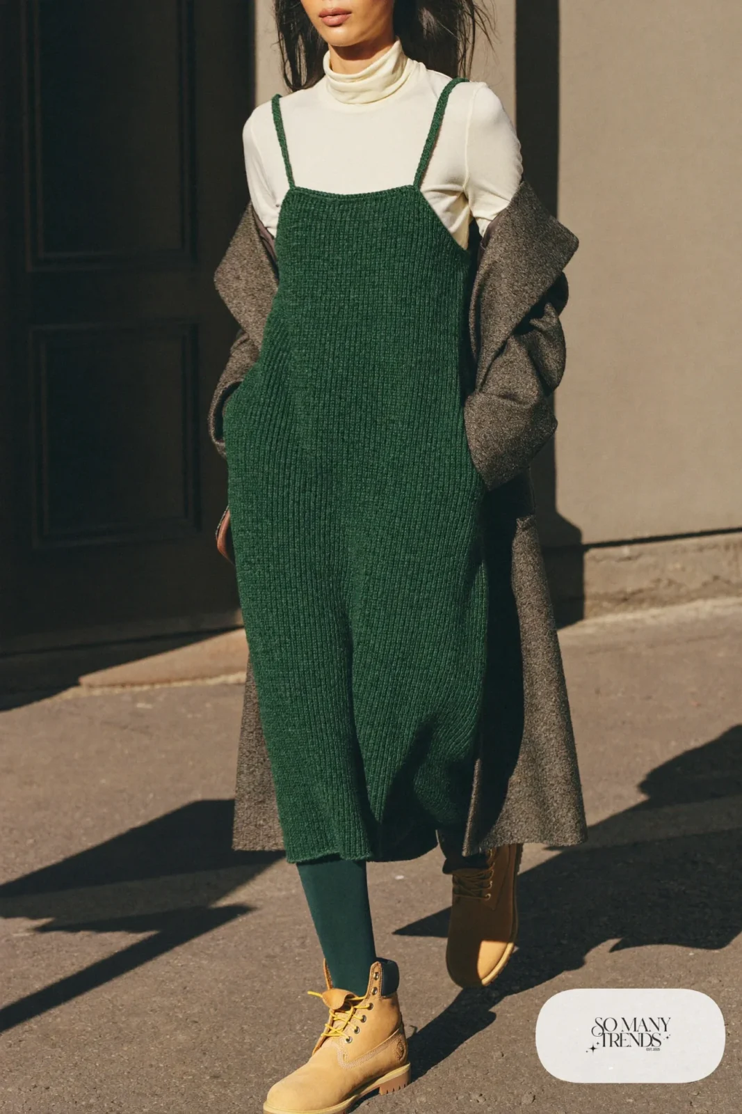 Woman in forest green knit slip dress over cream turtleneck, green tights and wheat Timberland-style boots, outfit 12