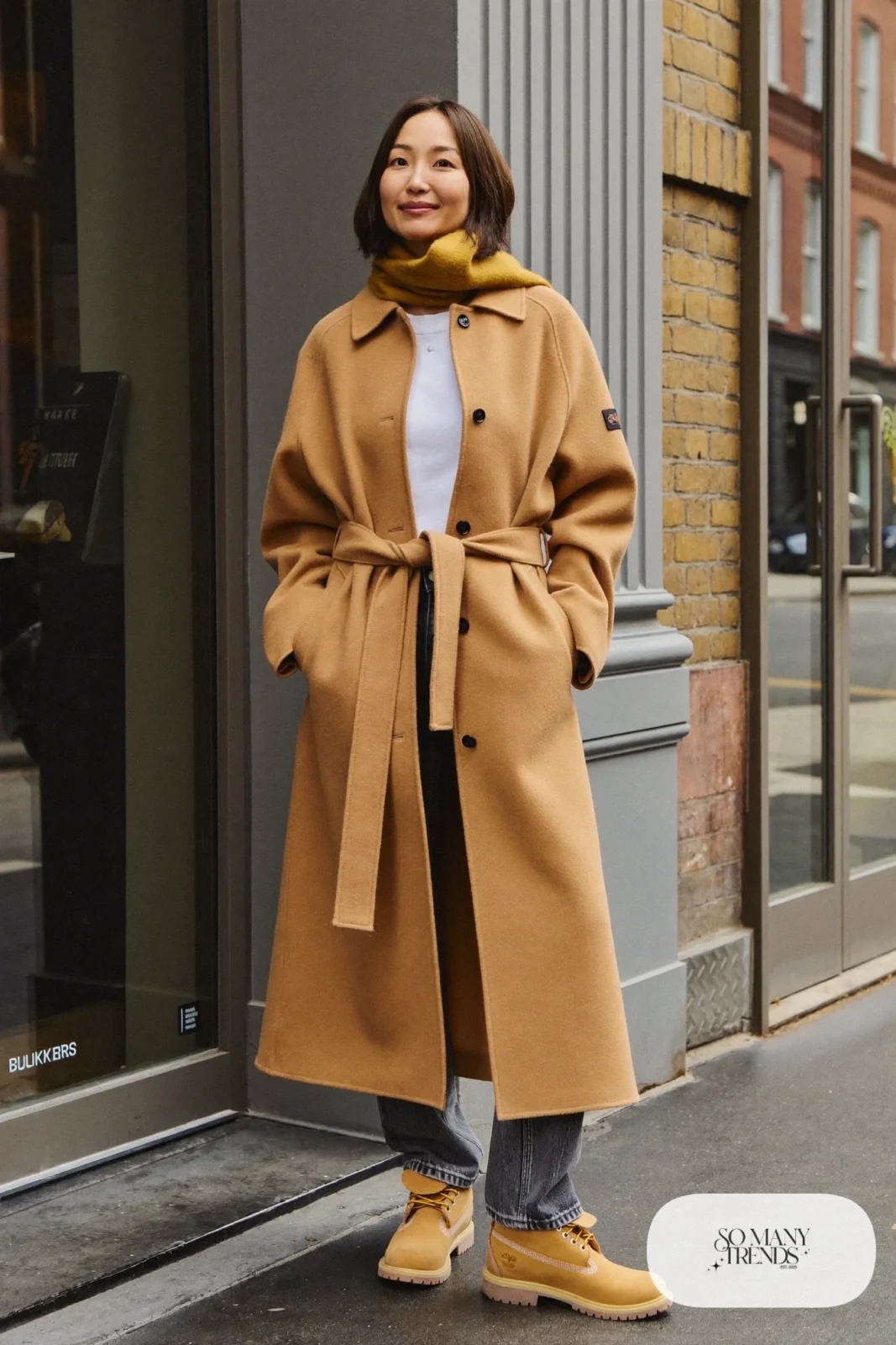 Woman in camel long cardigan coat, white tee, gray jeans and wheat Timberland-style boots, outfit 24
