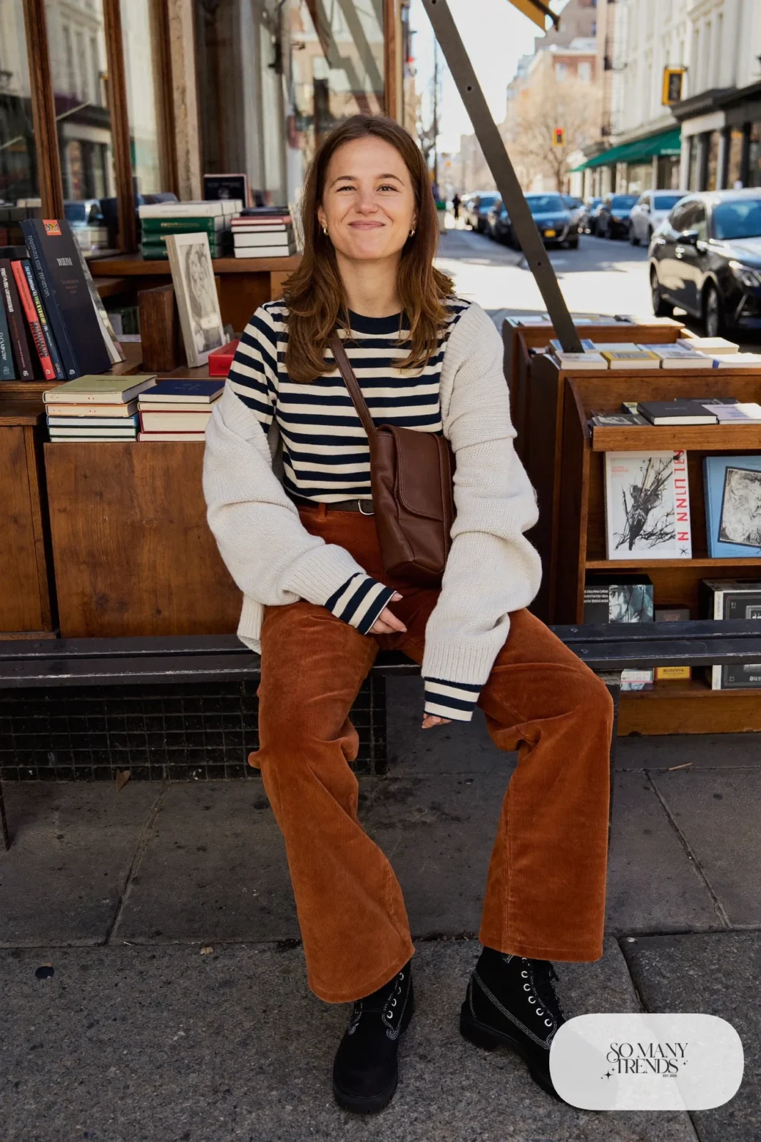 Woman in rust corduroy pants, cream cardigan, striped tee and black Timberland-style boots, outfit 28