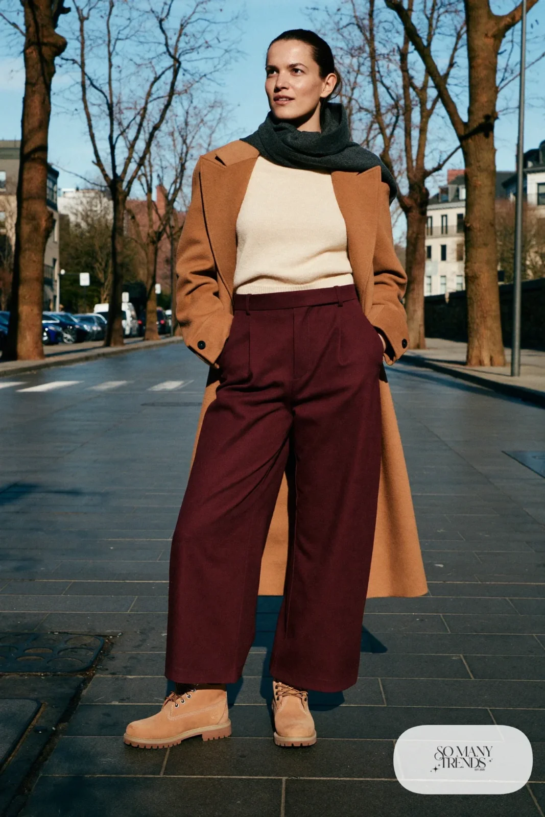 Woman in camel coat, cream knit, burgundy wide-leg pants and wheat Timberland-style boots, outfit 29