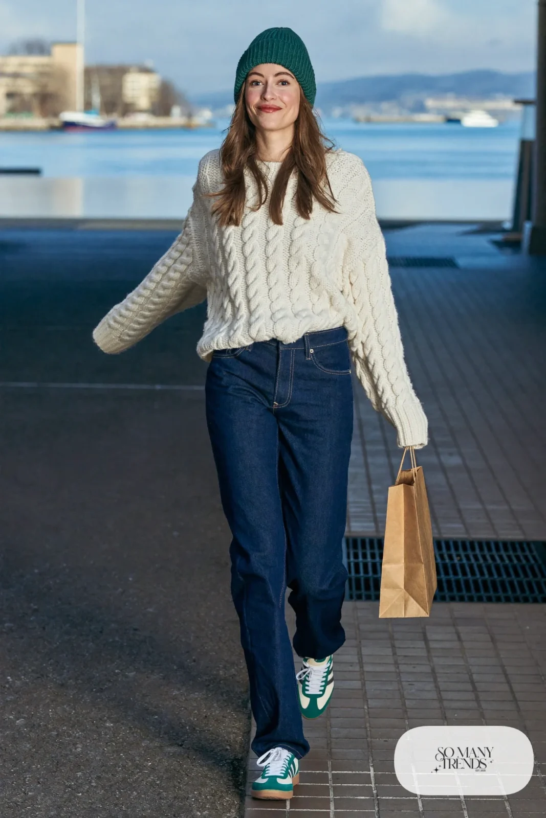 Cream cable-knit sweater, dark straight denim, forest green beanie and low retro sneakers, outfit 15
