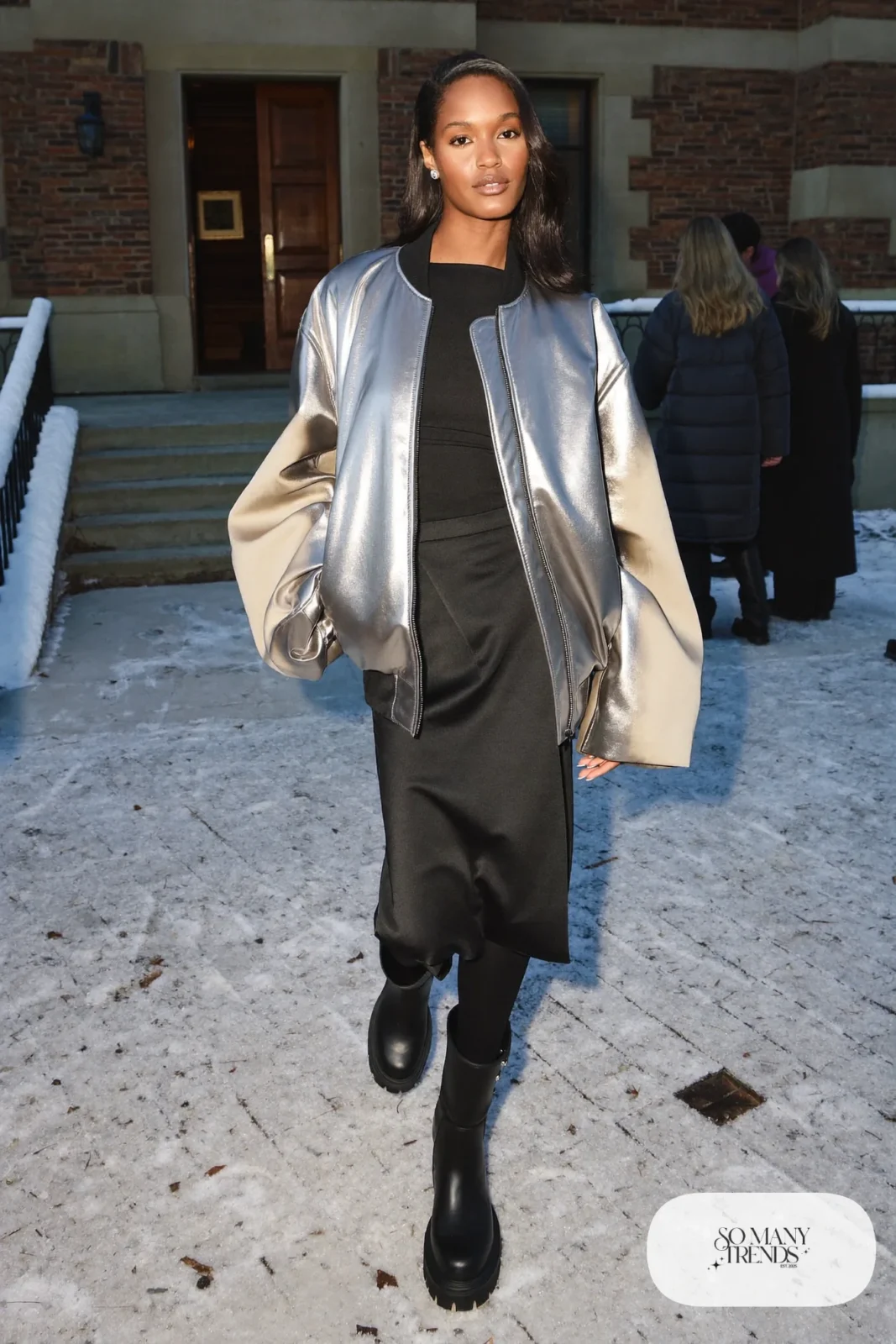 Woman in a silver metallic bomber jacket, black fitted top, black satin midi skirt and black chunky boots, New Year's Eve outfit 15