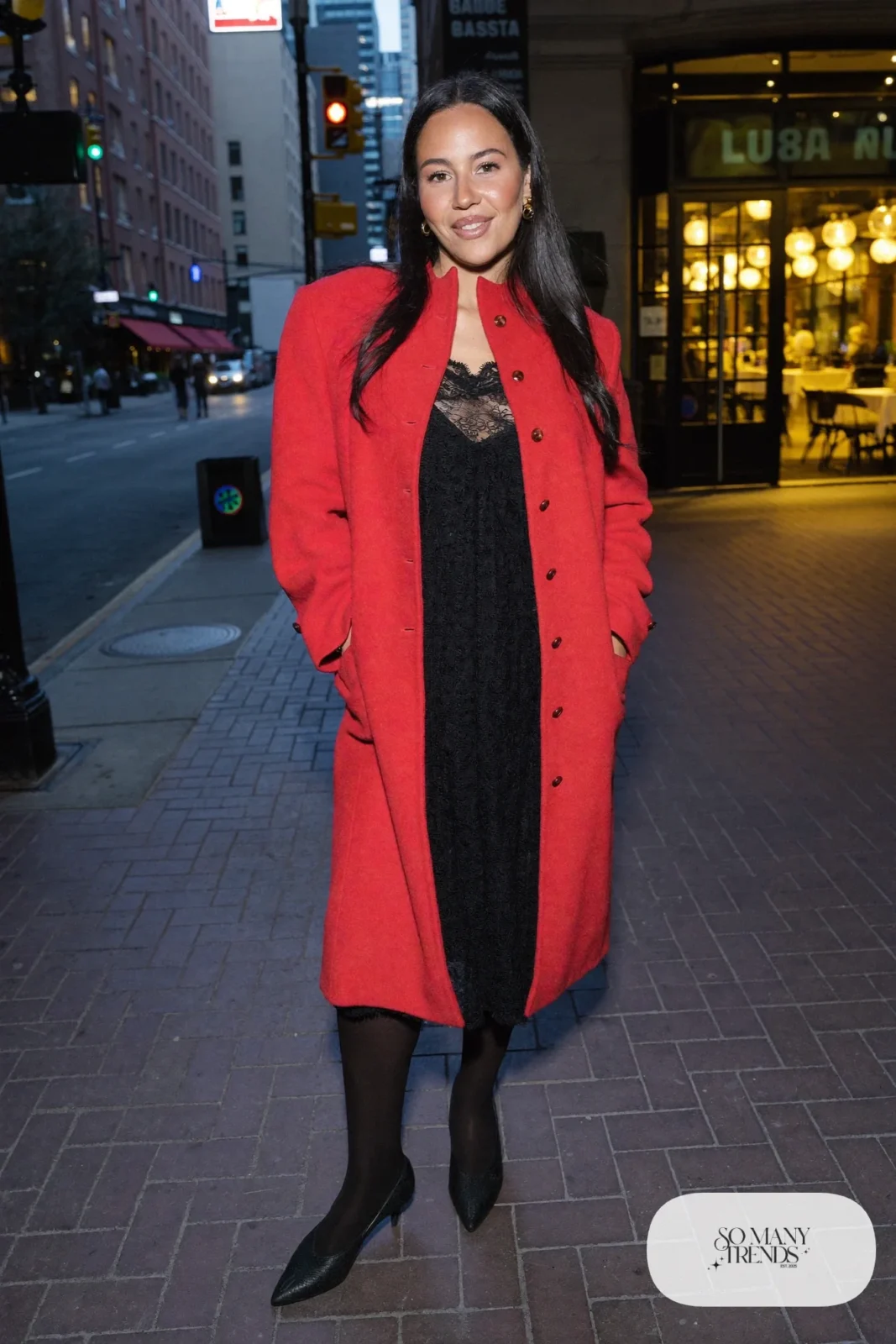 Woman in a black lace midi dress, long red wool coat and black pumps, look 8