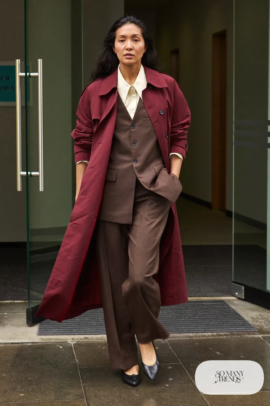 Woman in a burgundy trench coat over a chocolate-brown suit with black pointed flats, outfit 4