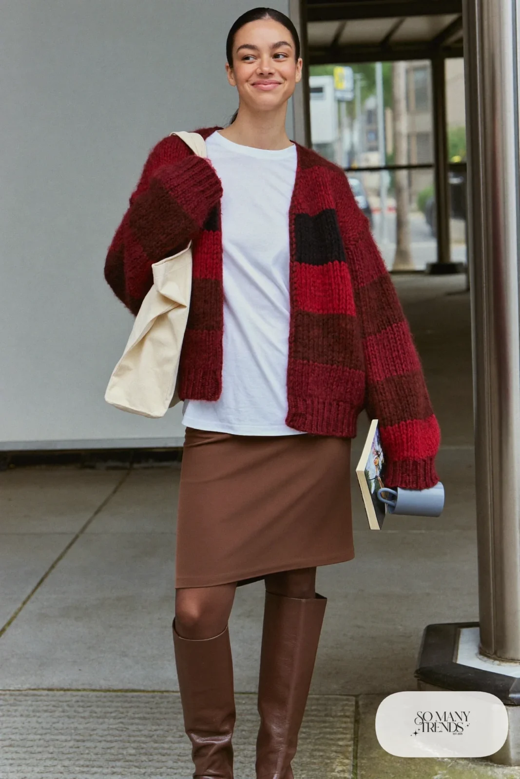 Woman in a chunky burgundy cardigan, chocolate midi skirt, white tee and tall brown boots, outfit 6