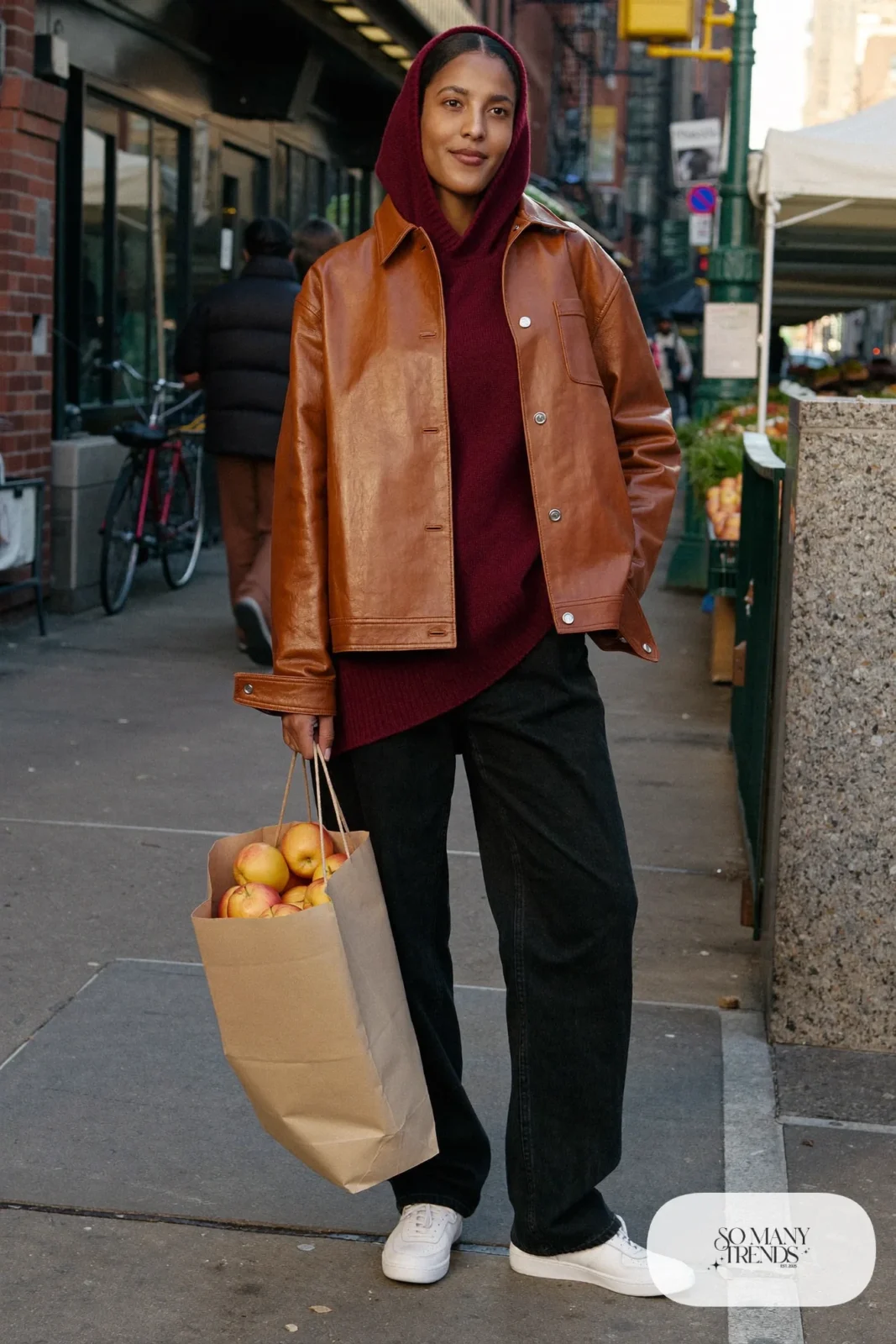 Woman in a cognac leather jacket, burgundy hoodie, black straight jeans and white sneakers, outfit 7