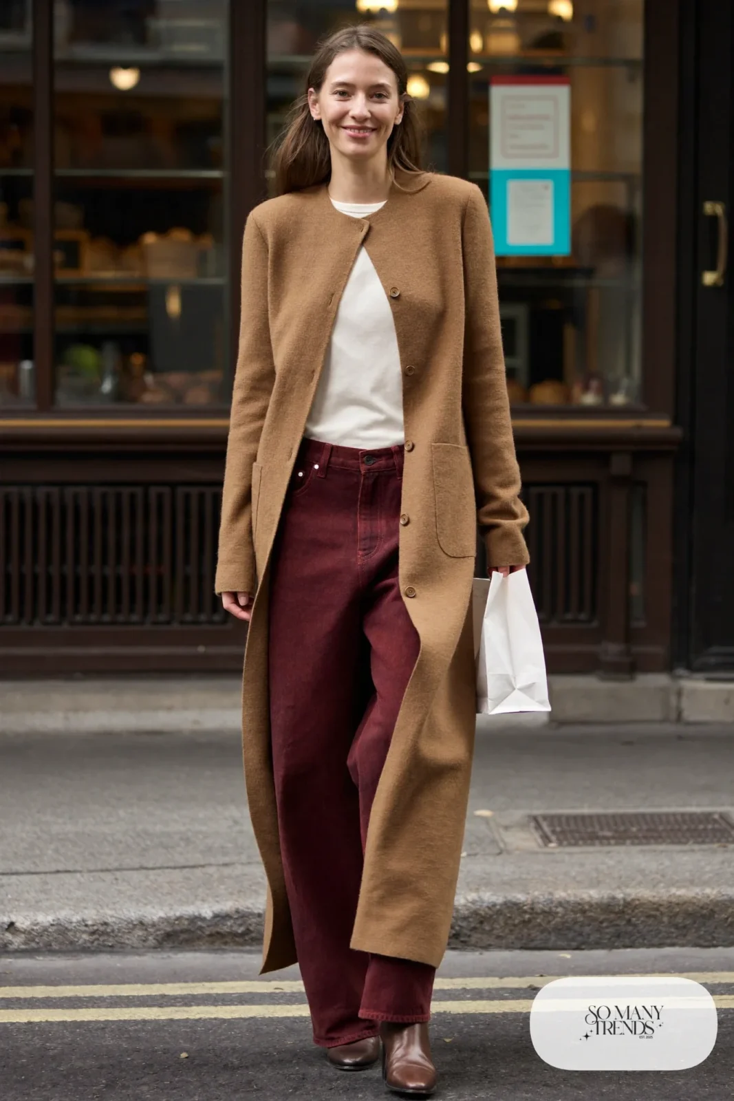 Woman in a camel long cardigan, burgundy wide-leg jeans, cream tee and pointed brown boots, outfit 13