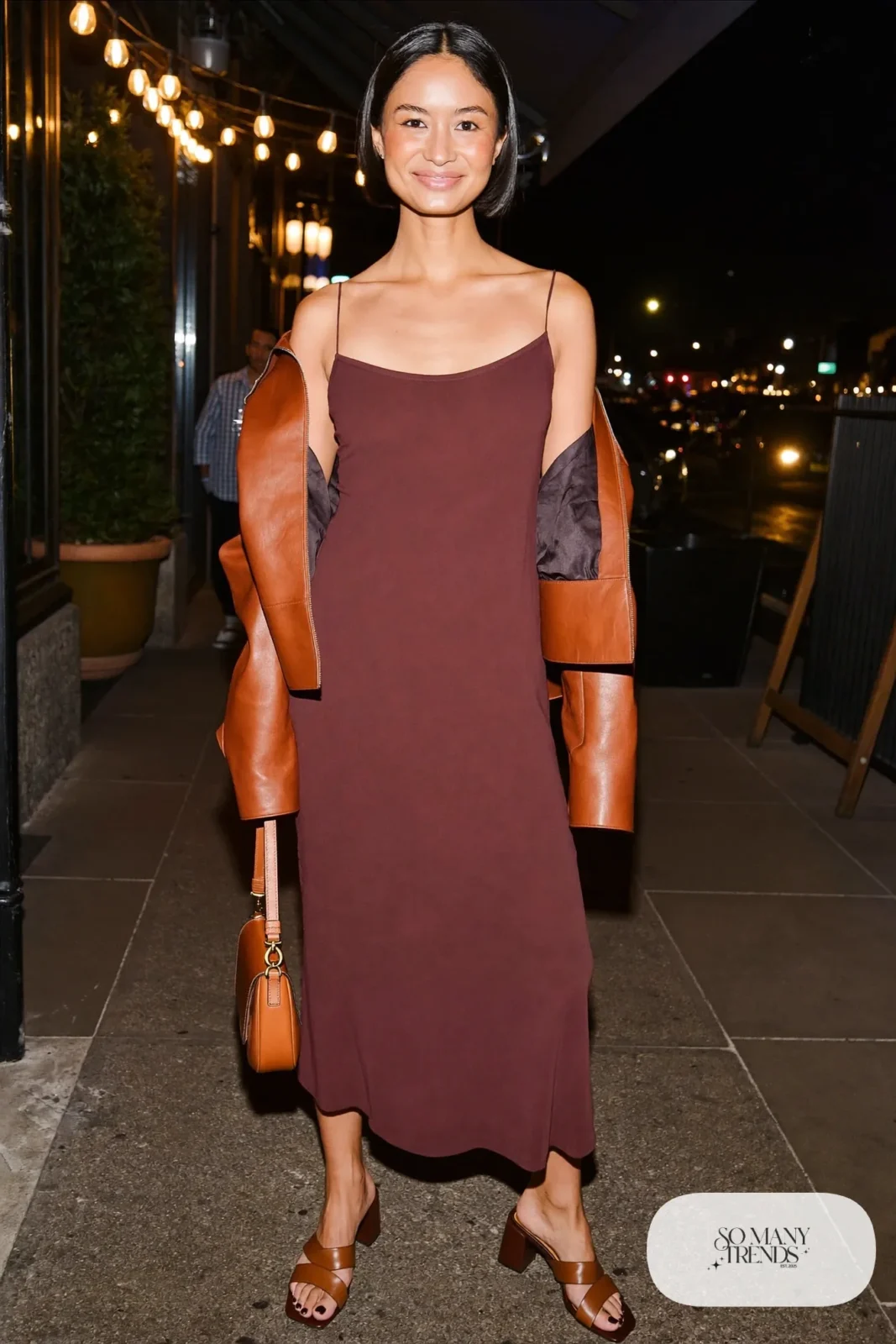 Woman in a burgundy slip dress, cognac leather jacket, bare legs and block heels, outfit 22