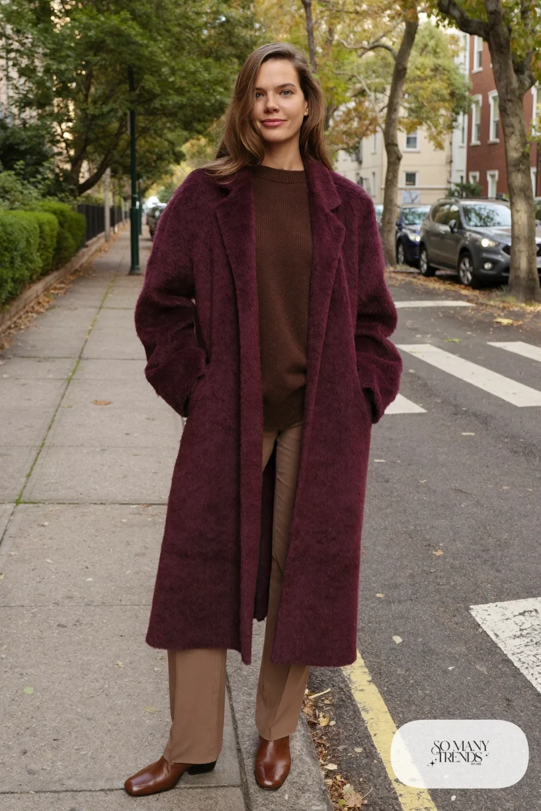 Woman in a long plum wool coat, chocolate brown knit sweater, camel straight pants and brown leather boots, outfit 1
