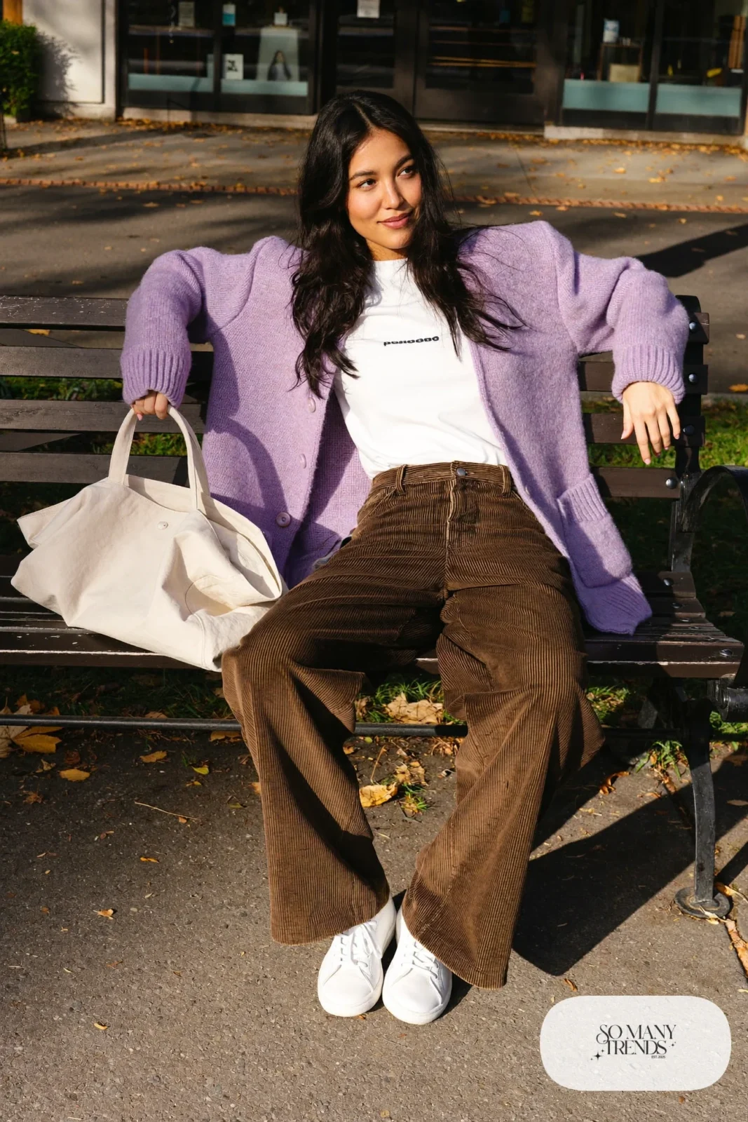 Woman in a lilac oversized cardigan, white tee, chocolate brown corduroy wide-leg pants and white leather sneakers, outfit 6