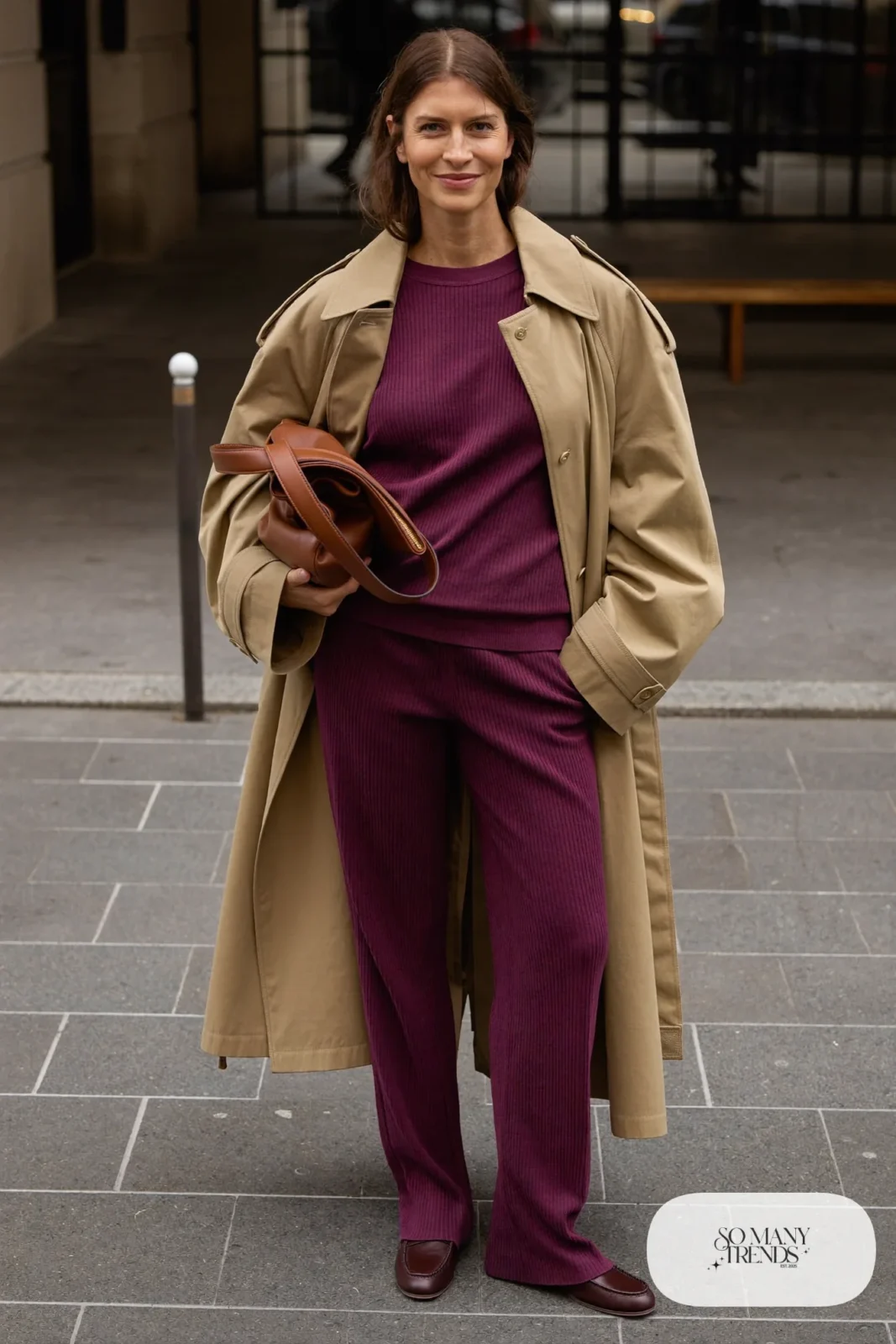 Woman in a tan trench coat, plum ribbed knit top and matching wide-leg knit pants with brown leather loafers, outfit 8