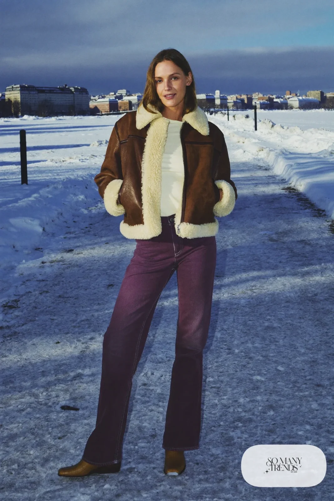 Woman in a brown shearling jacket, cream tee, plum straight jeans and tan leather boots, outfit 18