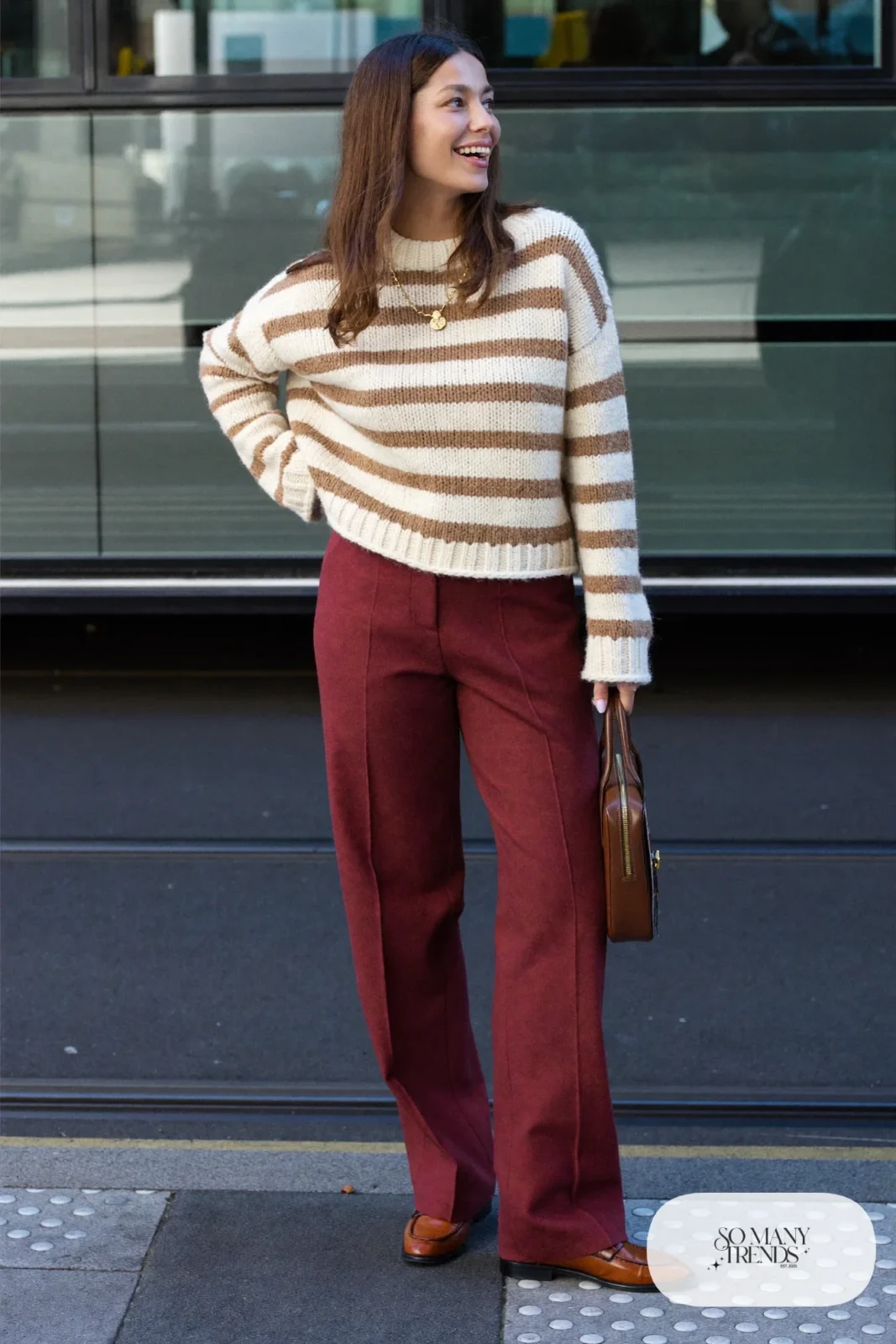Woman in an eggplant wool straight-leg pants, cream and tan striped knit sweater and brown leather loafers, outfit 19