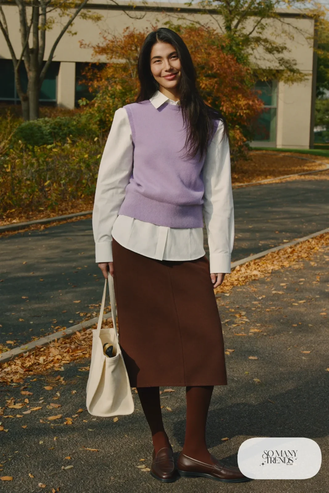 Woman in a lilac knit vest, white cotton shirt, brown wool midi skirt, brown tights and brown loafers, outfit 24