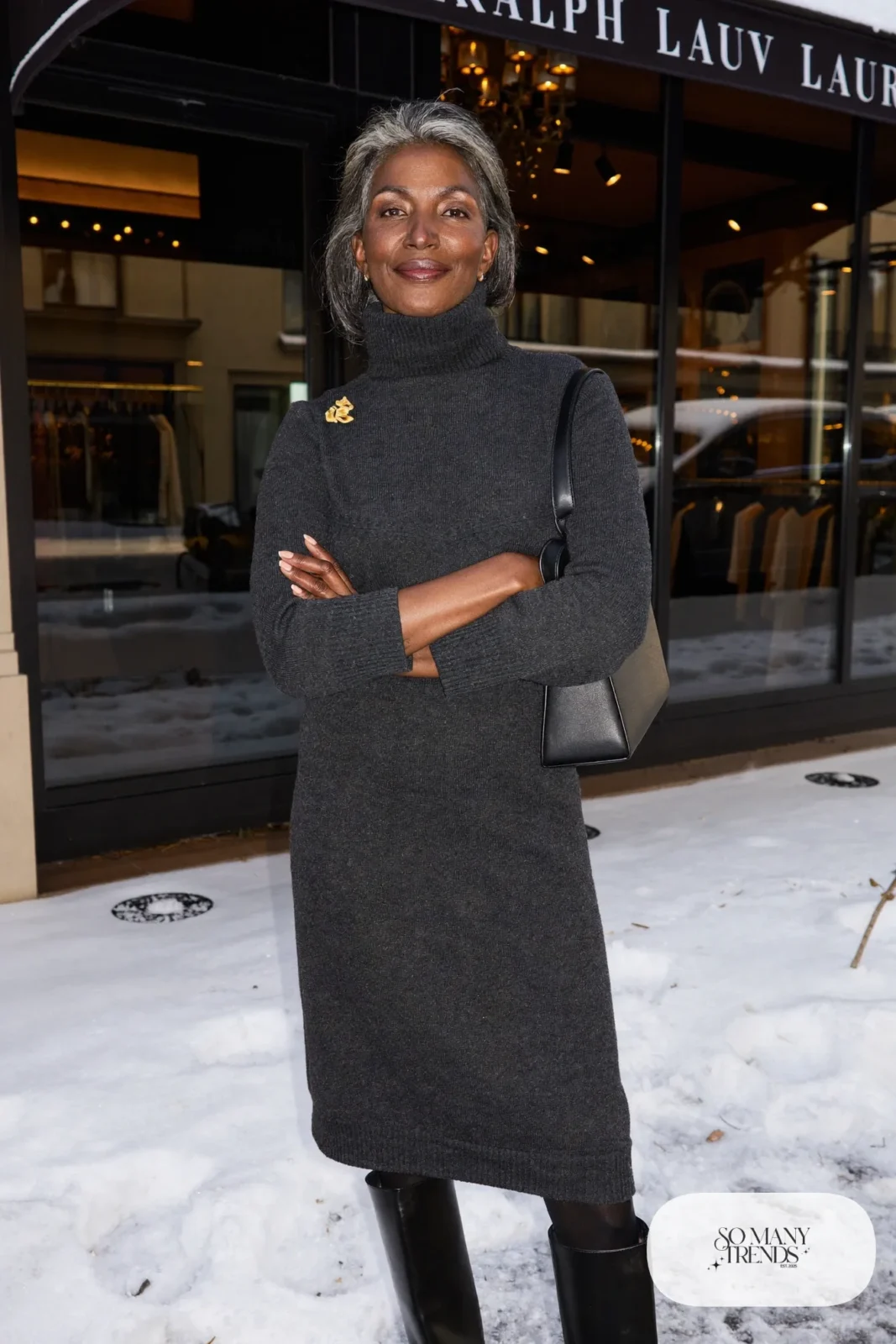 Woman over 50 in a charcoal turtleneck knit midi dress, gold brooch and black tall boots, Christmas outfit 9