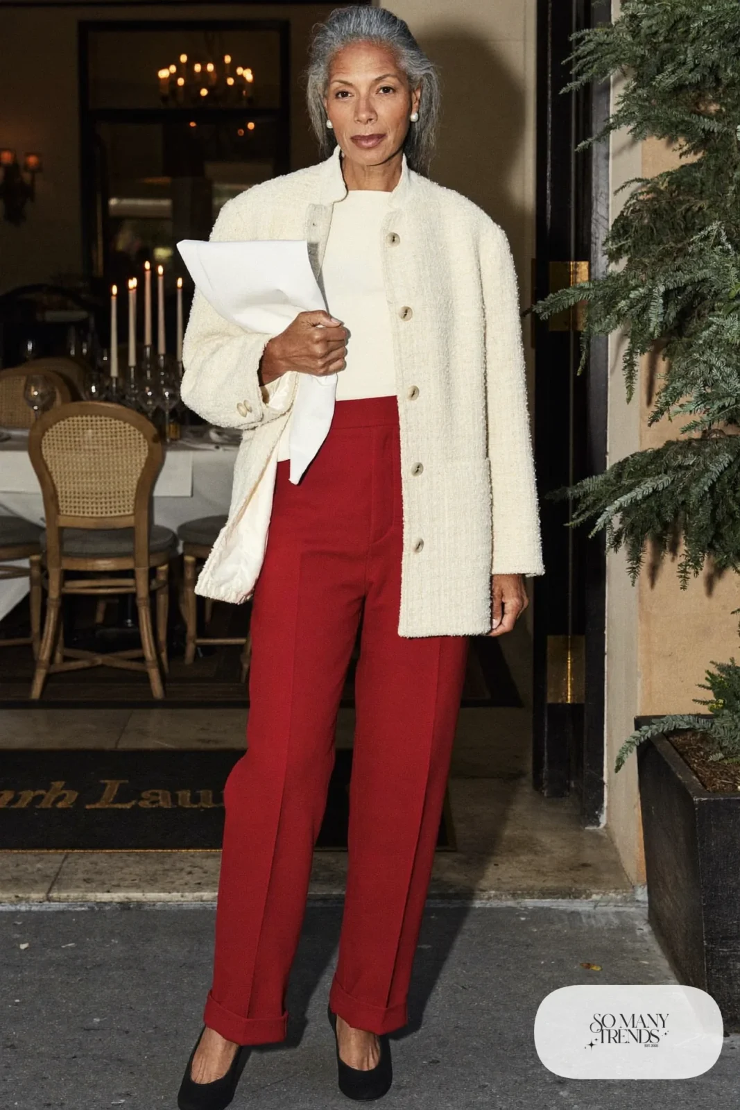 Woman over 50 in a cream tweed jacket, oxblood straight-leg pants, ivory knit top and black pumps, Christmas outfit 10