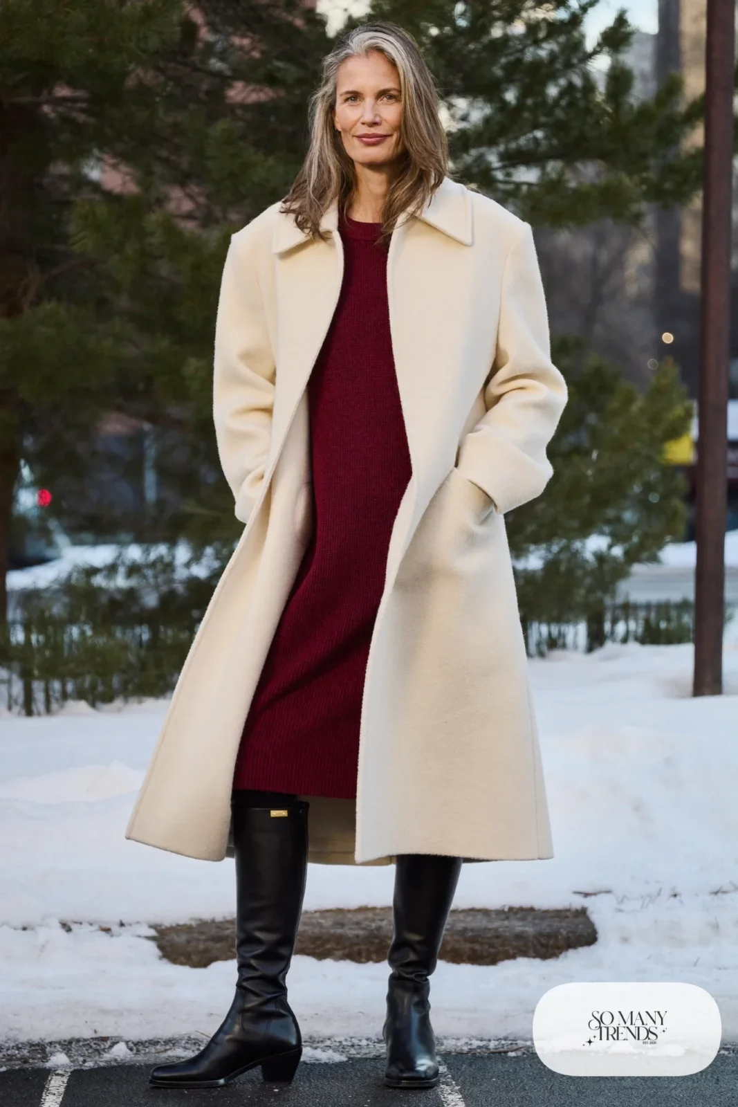 Woman over 50 in a cream wool coat, oxblood knit midi dress, black tights and black tall boots, Christmas outfit 19