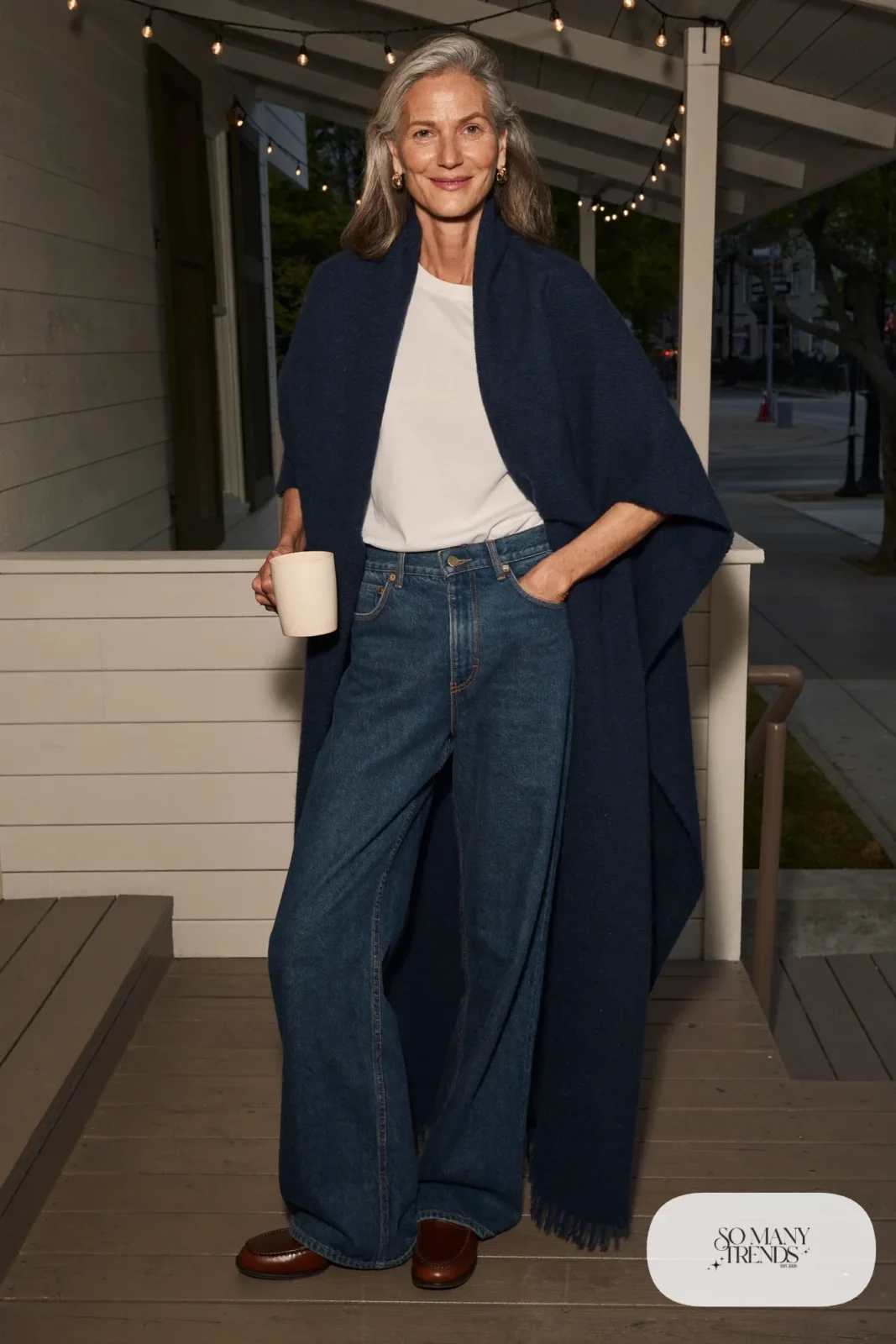 Woman over 50 in a navy cashmere wrap, white tee, dark wide-leg jeans and brown loafers, Christmas outfit 29