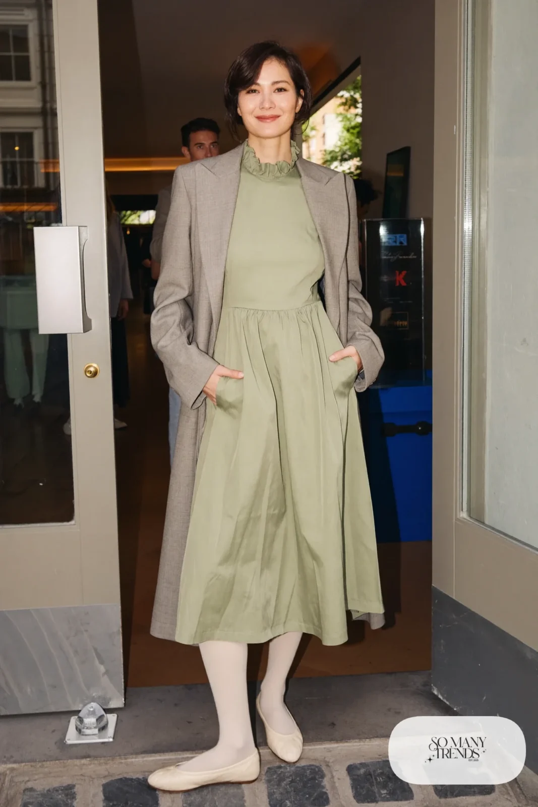 Woman in a sage green crepe midi dress with ruffled collar, cream tights and cream ballet flats, outfit 4