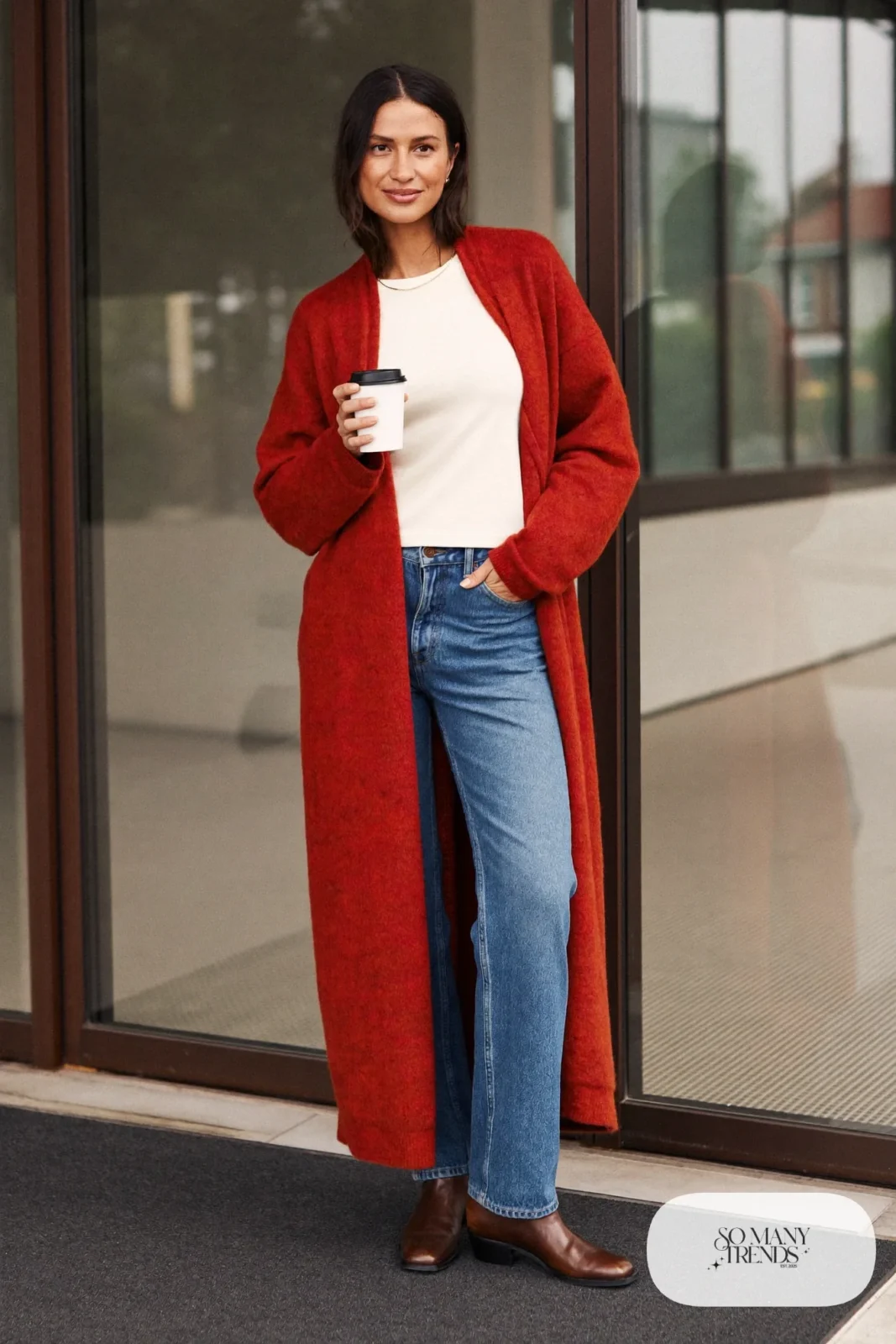 Woman in a long oxblood cardigan, ivory tee, straight blue jeans and brown ankle boots near a museum entrance, outfit 8