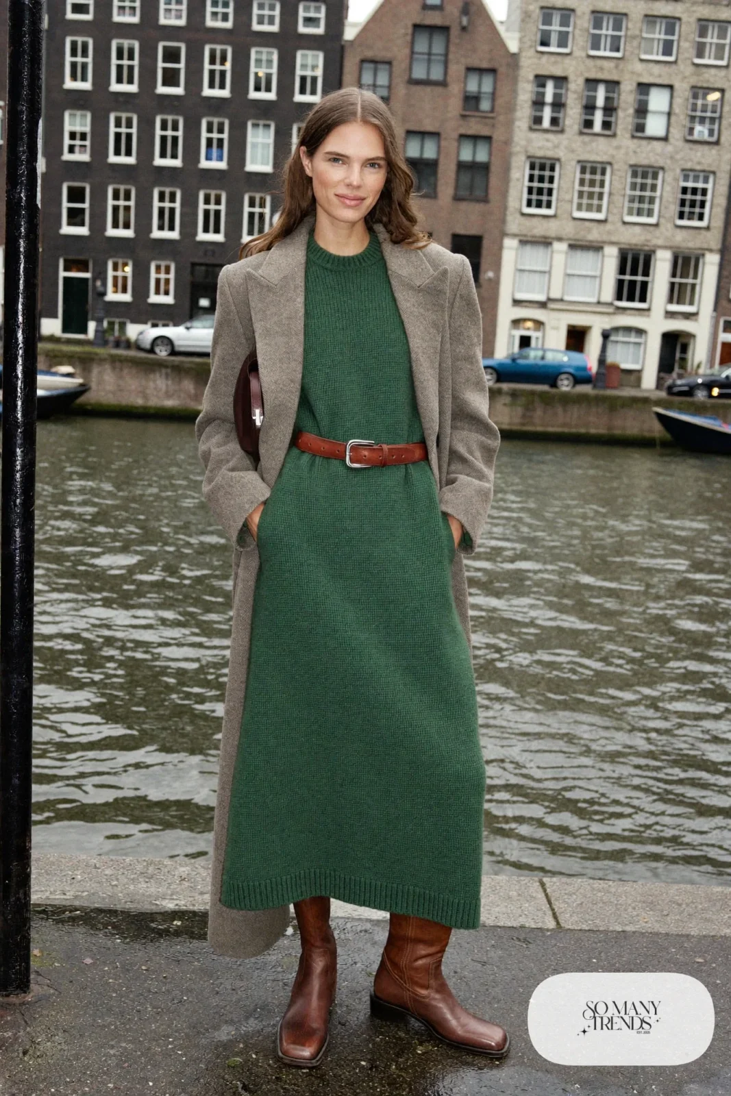 Woman in a forest green knit midi dress, gray wool coat, wide leather belt and tall brown boots on a canal street, outfit 23