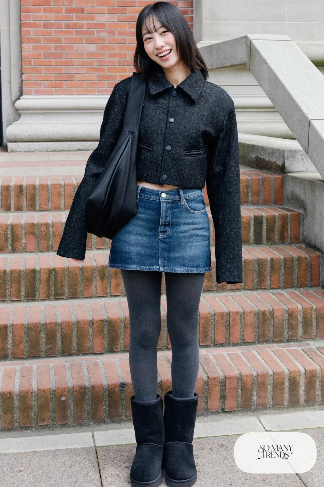 Woman in denim mini skirt, charcoal opaque tights, black cropped jacket and black Ugg mini boots, outfit 3