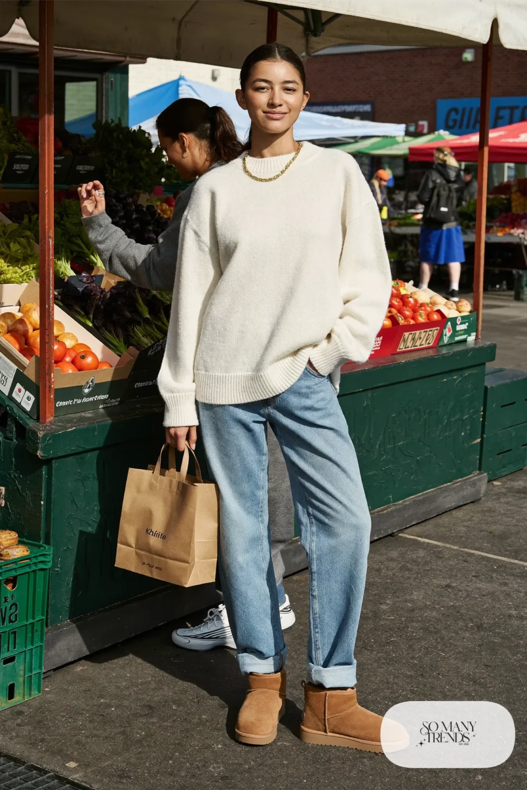 Woman in light blue straight jeans, cream chunky sweater and mocha Ugg mini boots, outfit 7