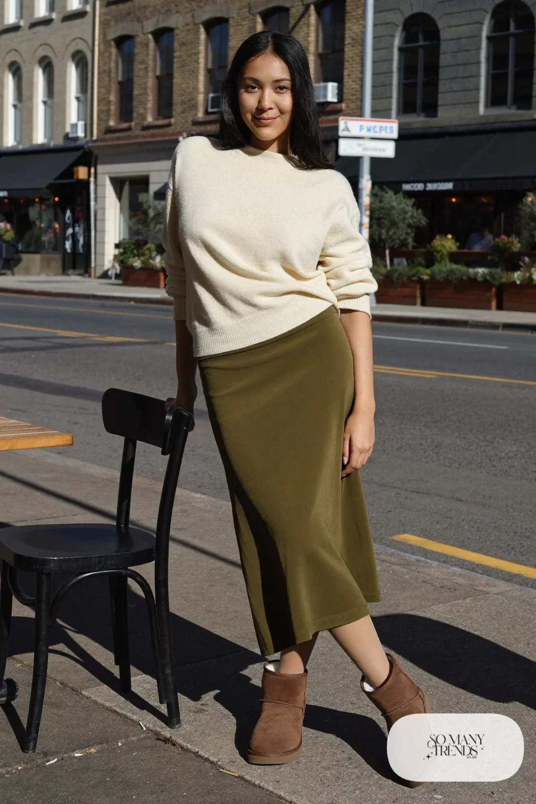 Woman in olive midi skirt, cream sweater, sheer nude tights and chocolate Ugg mini boots, outfit 23