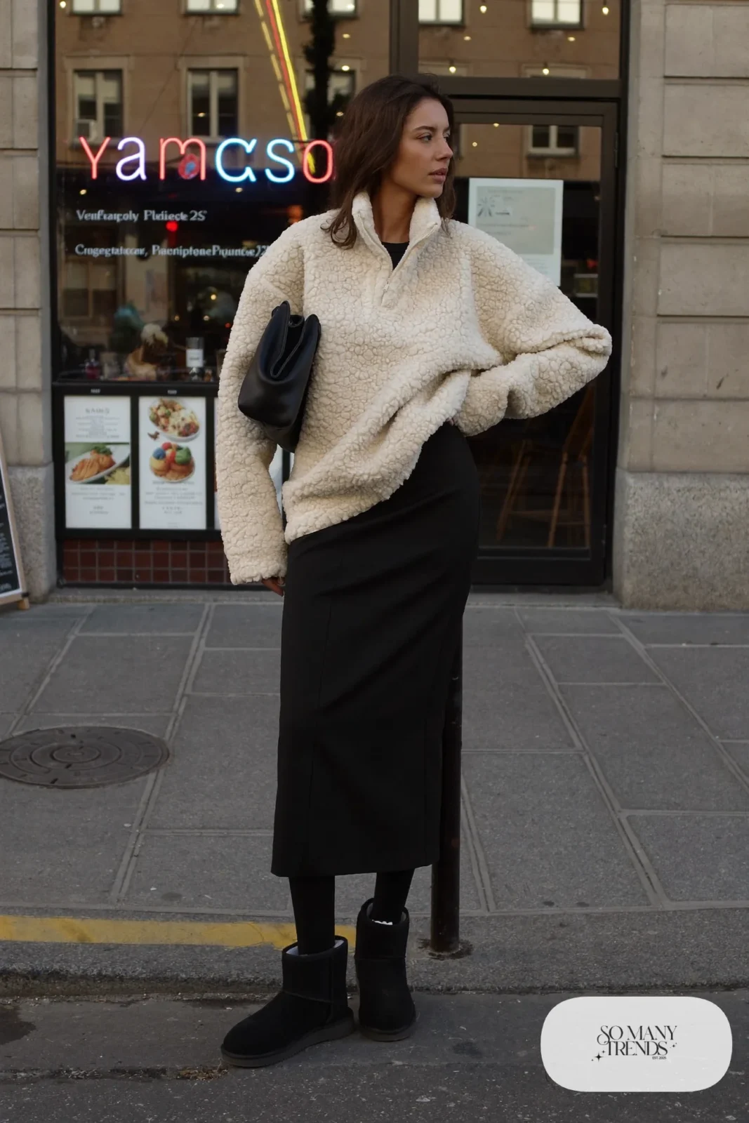 Woman in black column midi skirt, cream fleece pullover, black opaque tights and black Ugg mini boots, outfit 28