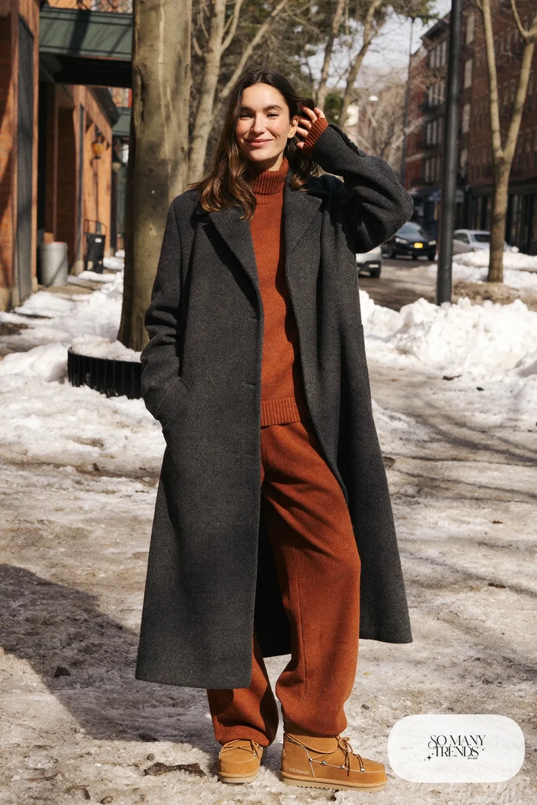 Woman in a rust knit sweater and matching wide pants, long charcoal coat and tan Sorel boots, outfit 11