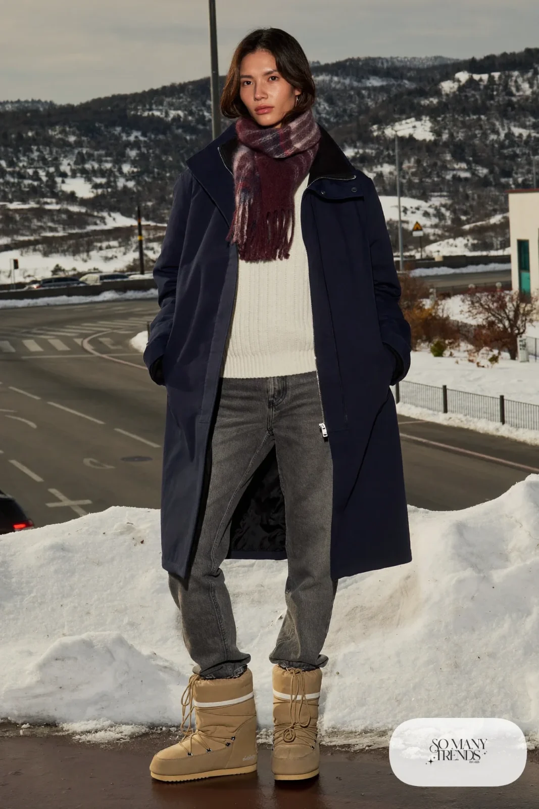 Woman in a navy parka, burgundy plaid scarf, gray jeans and tan Sorel boots, outfit 24