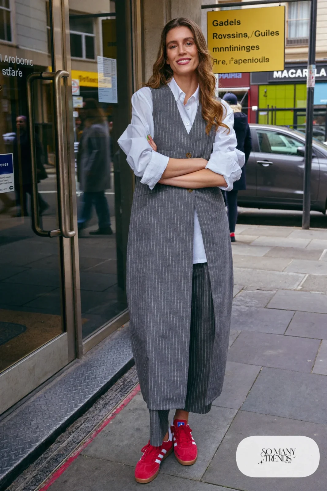 Woman in a gray pinstripe vest and matching pants, white poplin shirt and red Adidas Gazelle sneakers, outfit 10