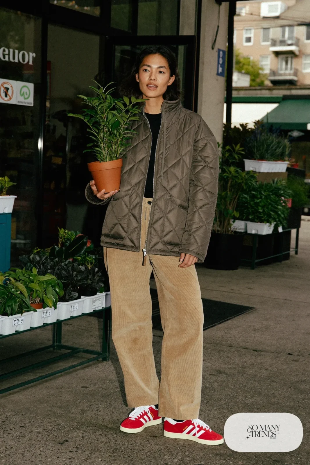 Woman in an olive quilted jacket, tan wide corduroy pants, cream sweater and red Adidas Gazelle sneakers, outfit 24