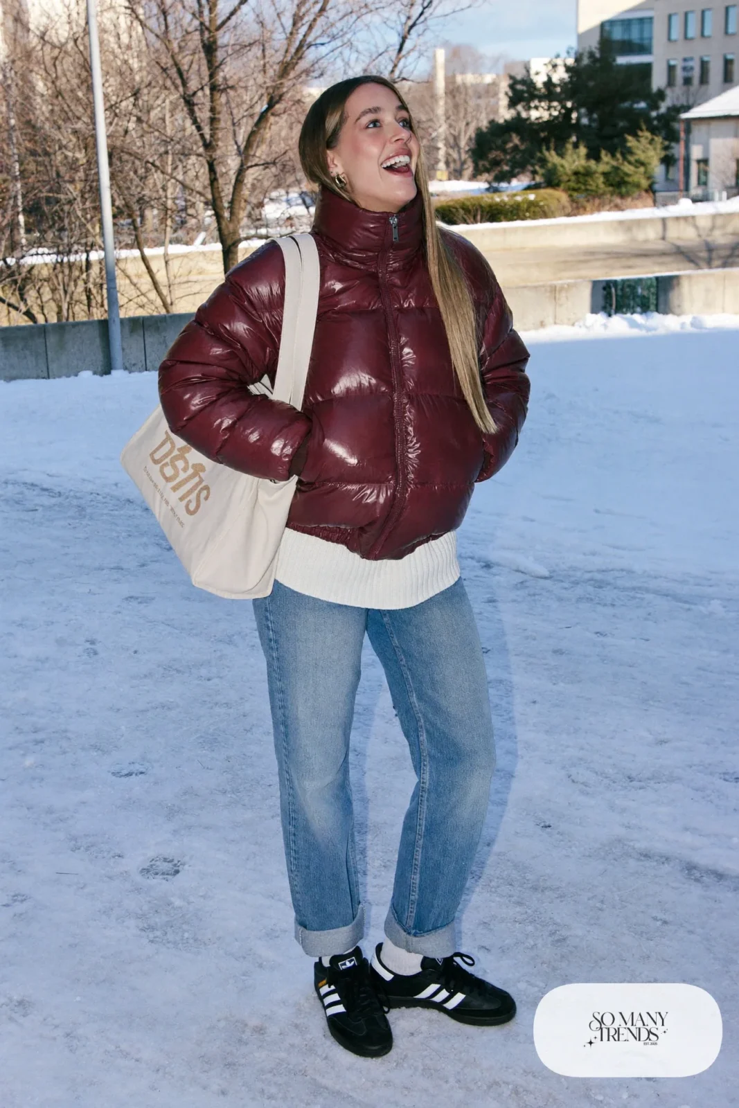 Woman in burgundy puffer jacket, white knit, light wash jeans and black Adidas Campus sneakers, outfit 24
