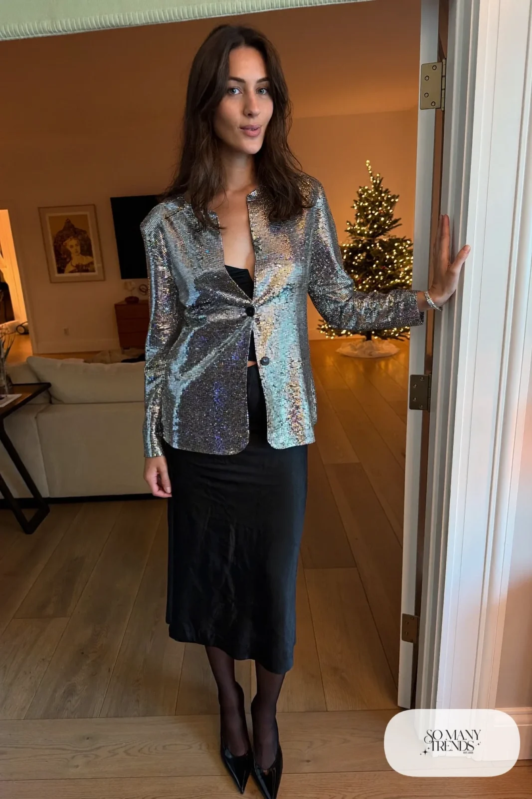 Woman in a chrome silver sequin cardigan over a black camisole and black satin midi skirt with black ankle strap heels, New Year's Eve outfit 8