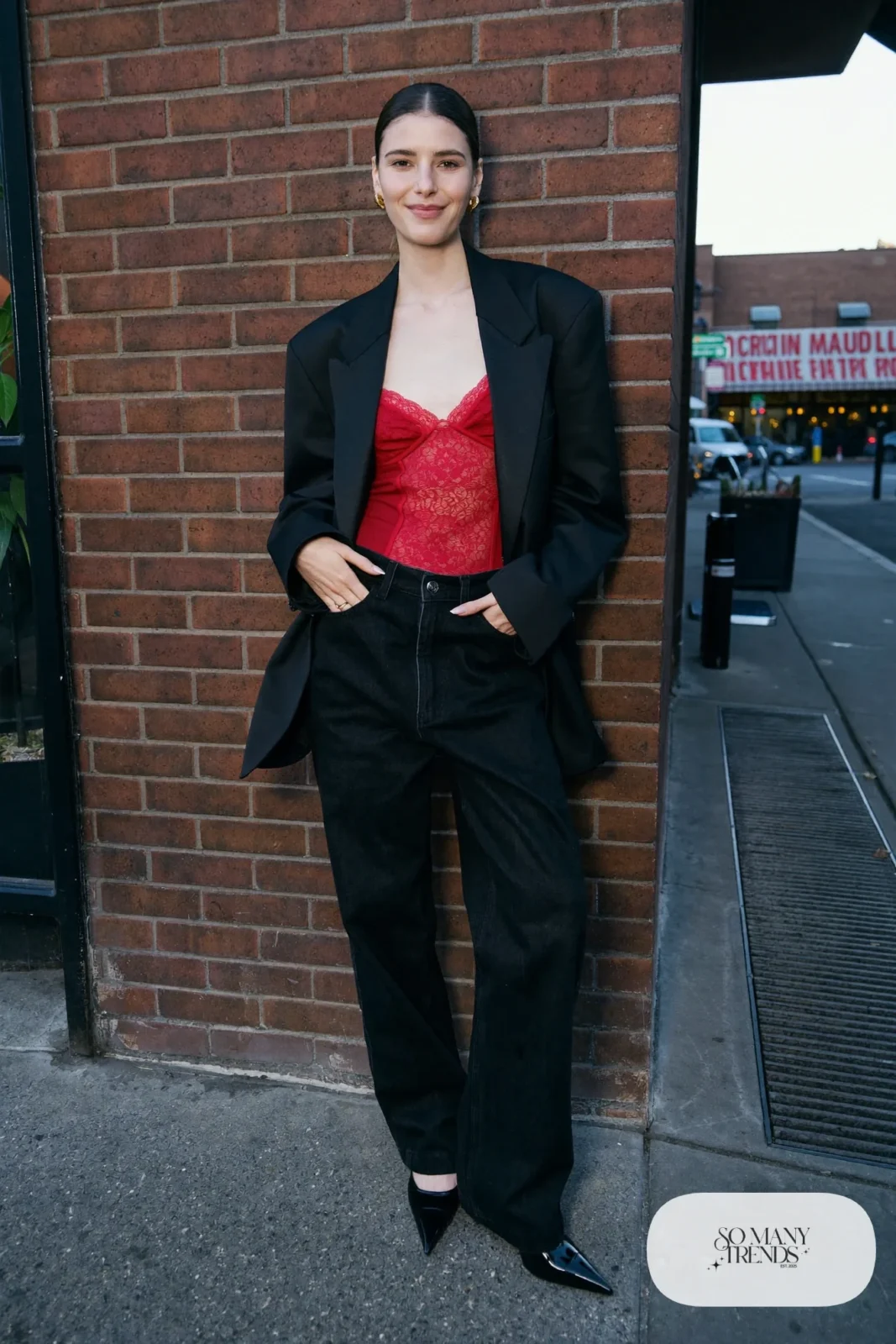 Woman in black straight jeans, red lace camisole, black blazer and black heels, look 15