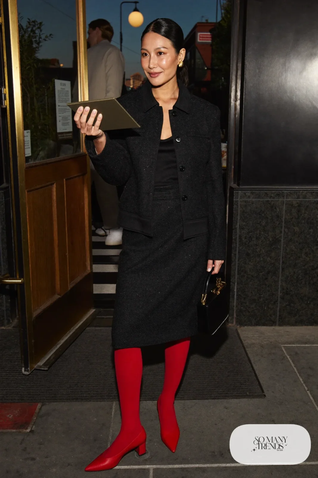 Woman in a black tweed jacket and skirt set with red pumps, look 21