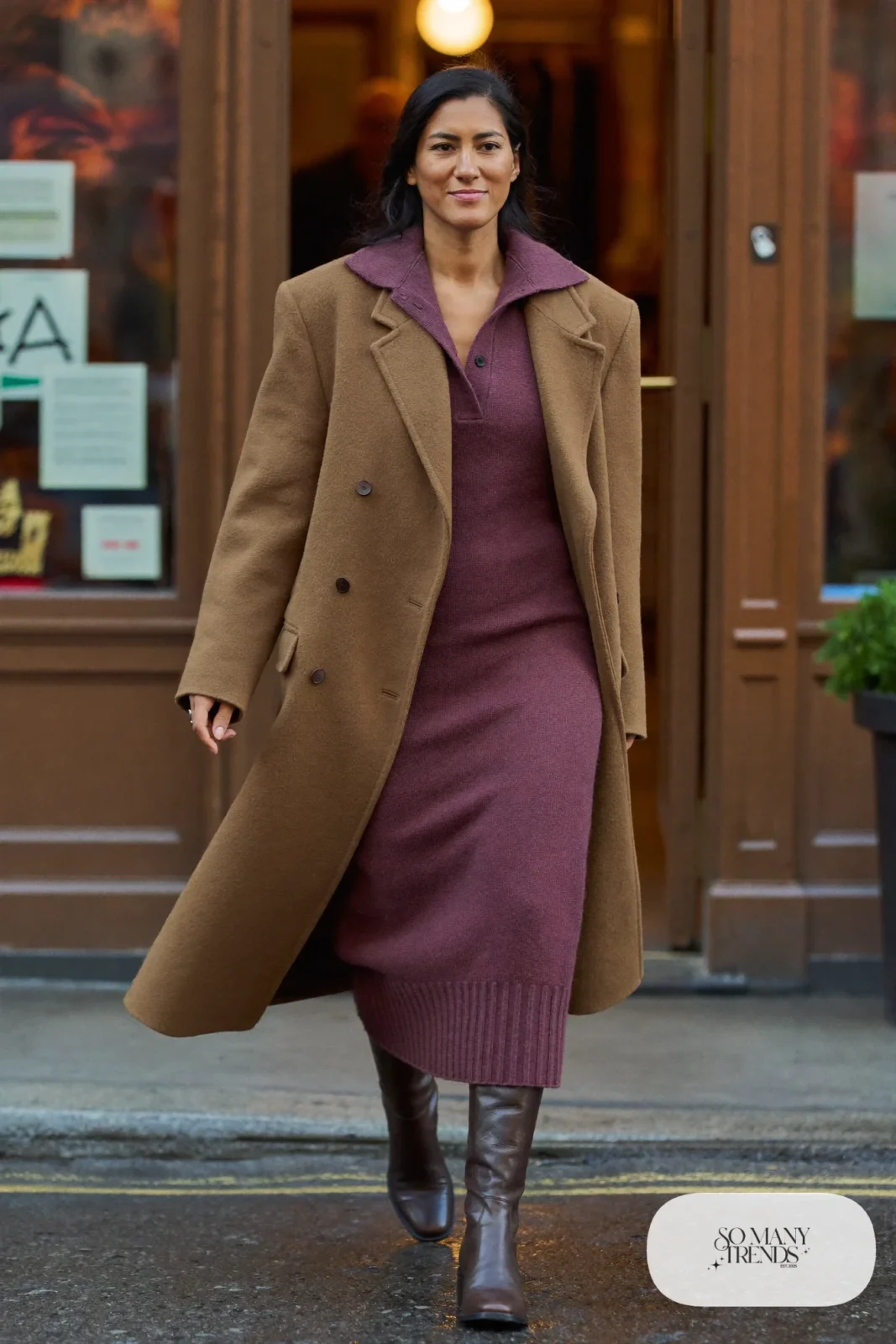Woman in a plum knit midi dress, camel belted wool coat, black sheer tights and brown leather boots, outfit 5