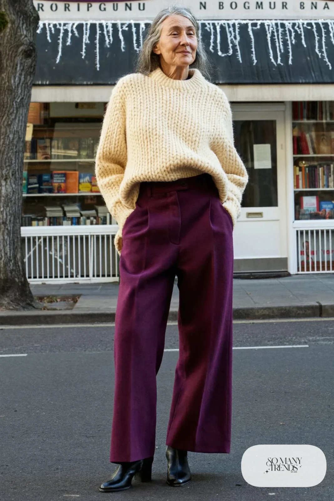 Woman over 50 in a plum wool wide-leg pants, cream chunky sweater and black ankle boots, Christmas outfit 23
