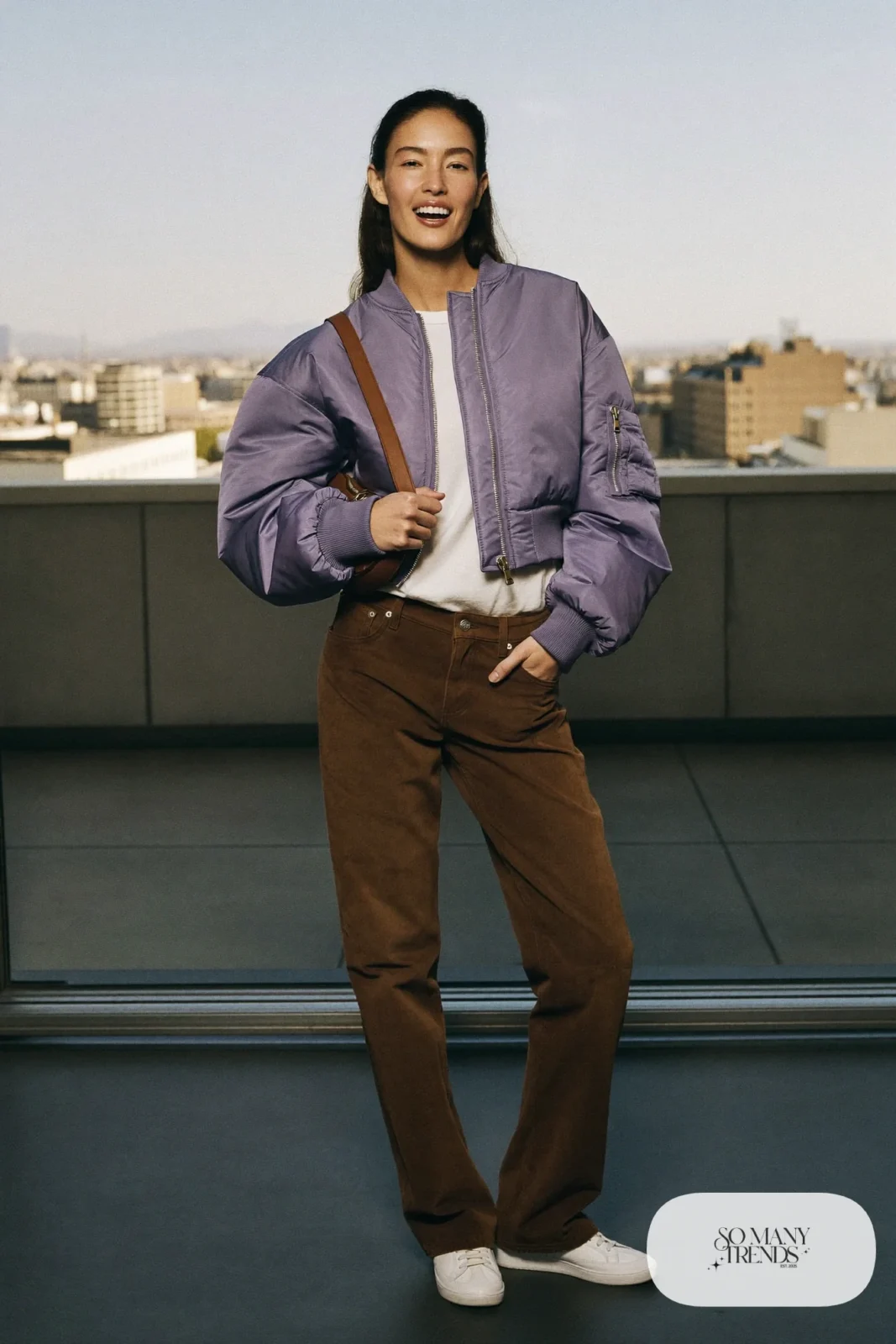 Woman in a lavender satin-free bomber jacket, white tee, brown faux suede straight pants and white sneakers, outfit 22