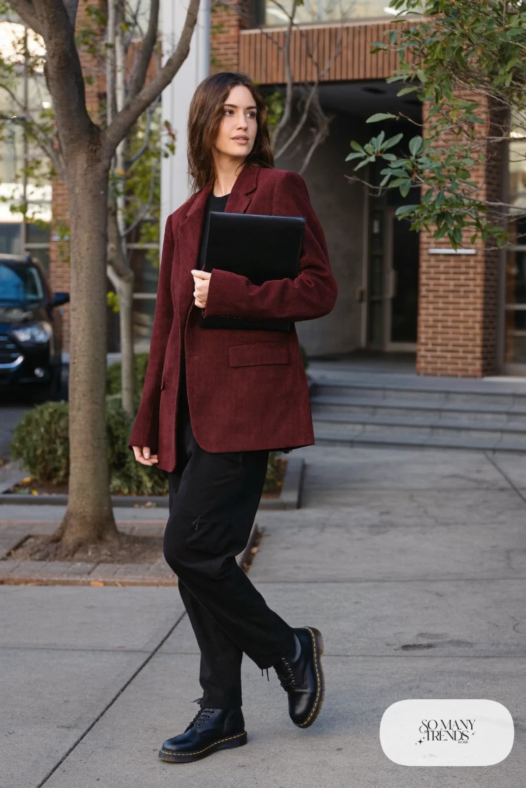 Woman in burgundy corduroy blazer, black fitted top, black straight pants and black Doc Martens boots, outfit 5