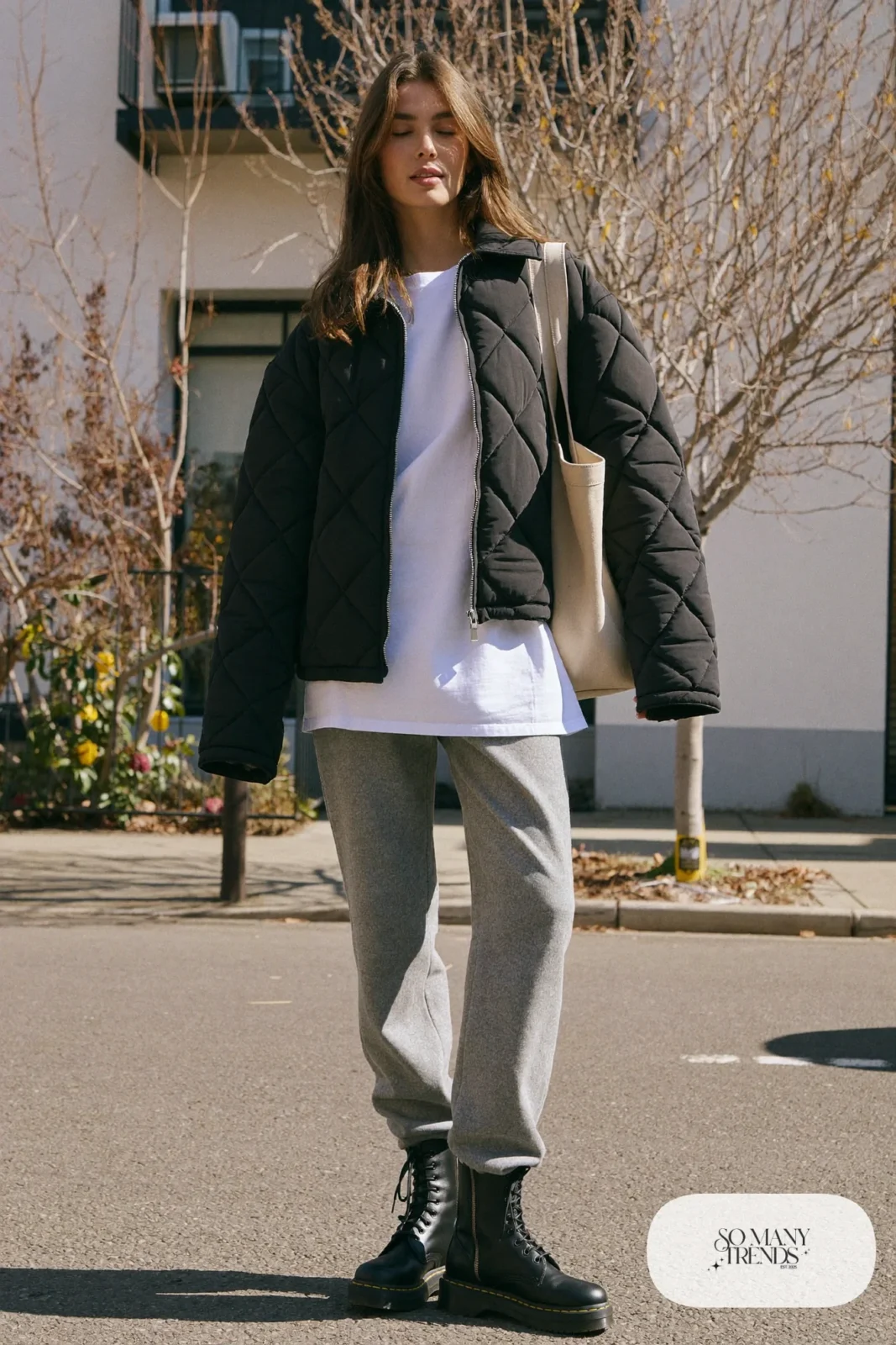 Woman in black quilted jacket, white tee, relaxed gray pants and black Doc Martens boots, outfit 30