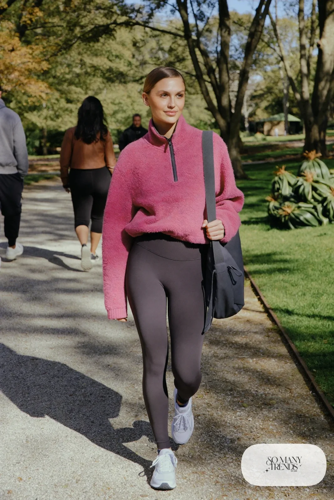 Woman in a rose pink fleece pullover, charcoal high-waist leggings, light gray sneakers and a gray tote, outfit 9