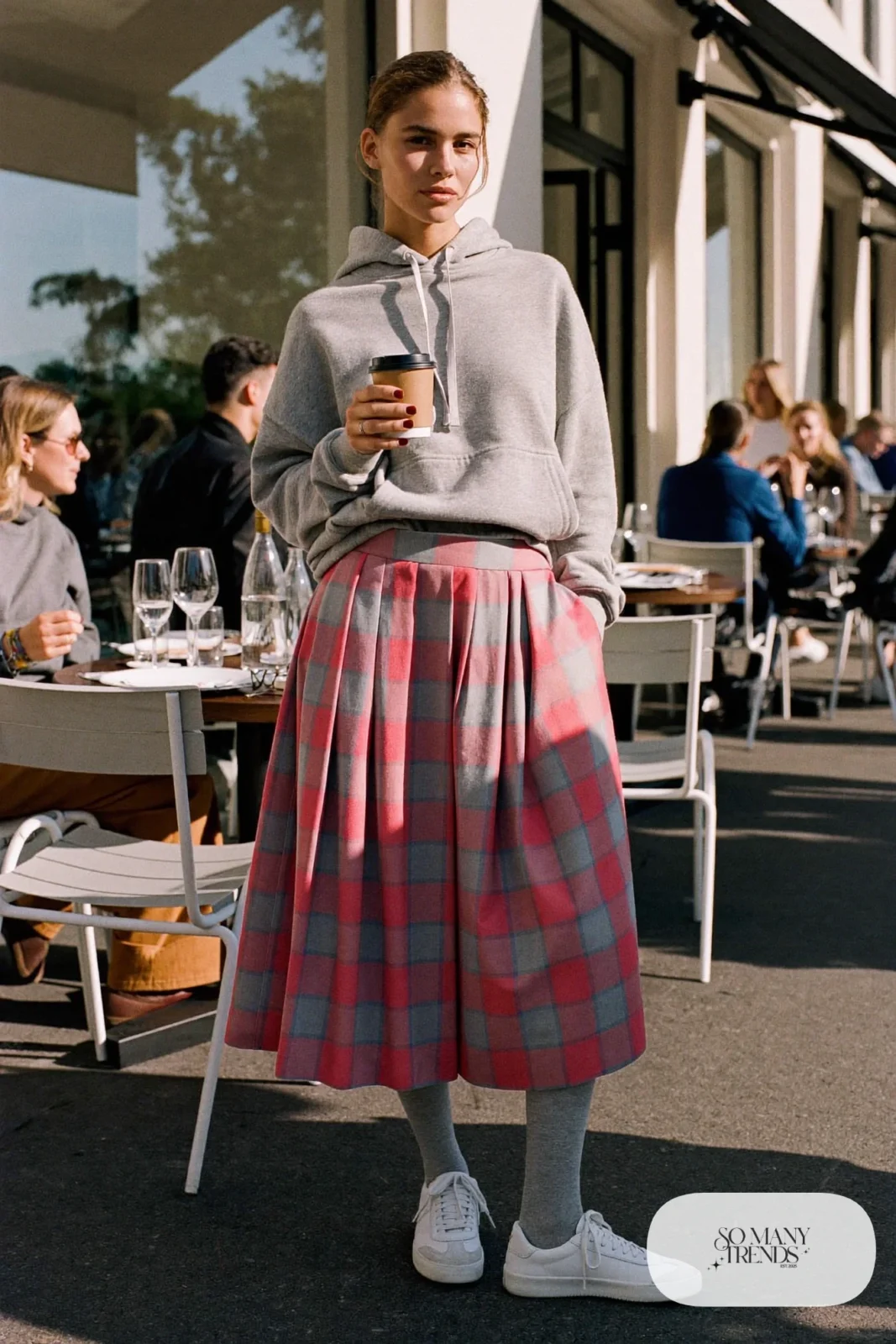 Woman in a gray hoodie, pink and gray plaid pleated midi skirt, gray tights and white sneakers, outfit 10