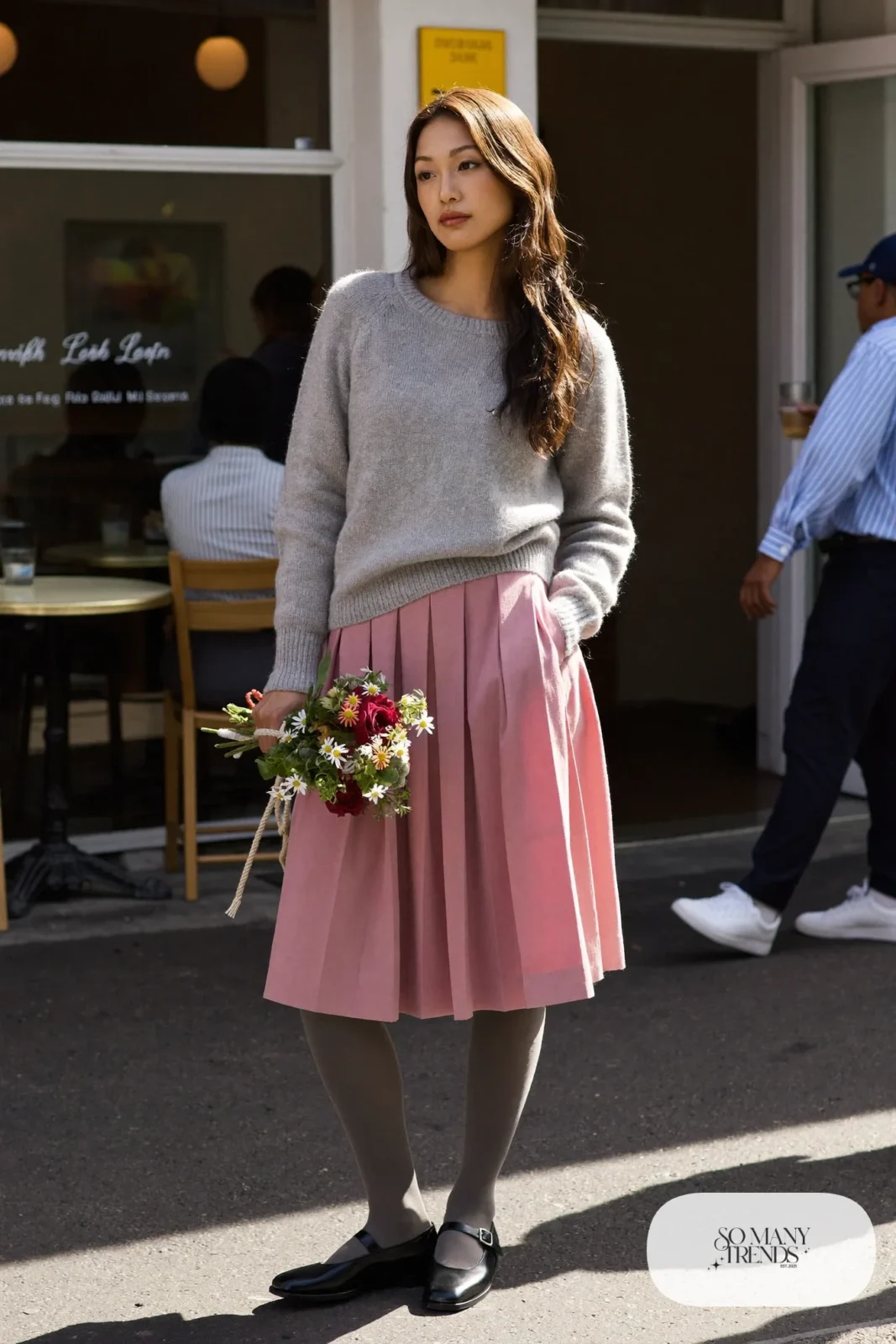 Woman in a gray cashmere sweater, pink pleated midi skirt, gray tights and black mary jane shoes, outfit 19